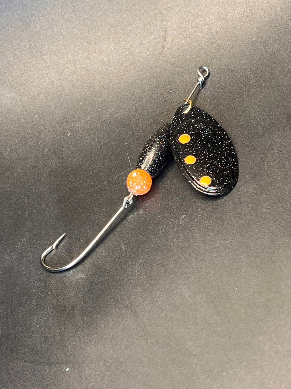 Speckled black-and-orange inline spinner lure with treble hook
