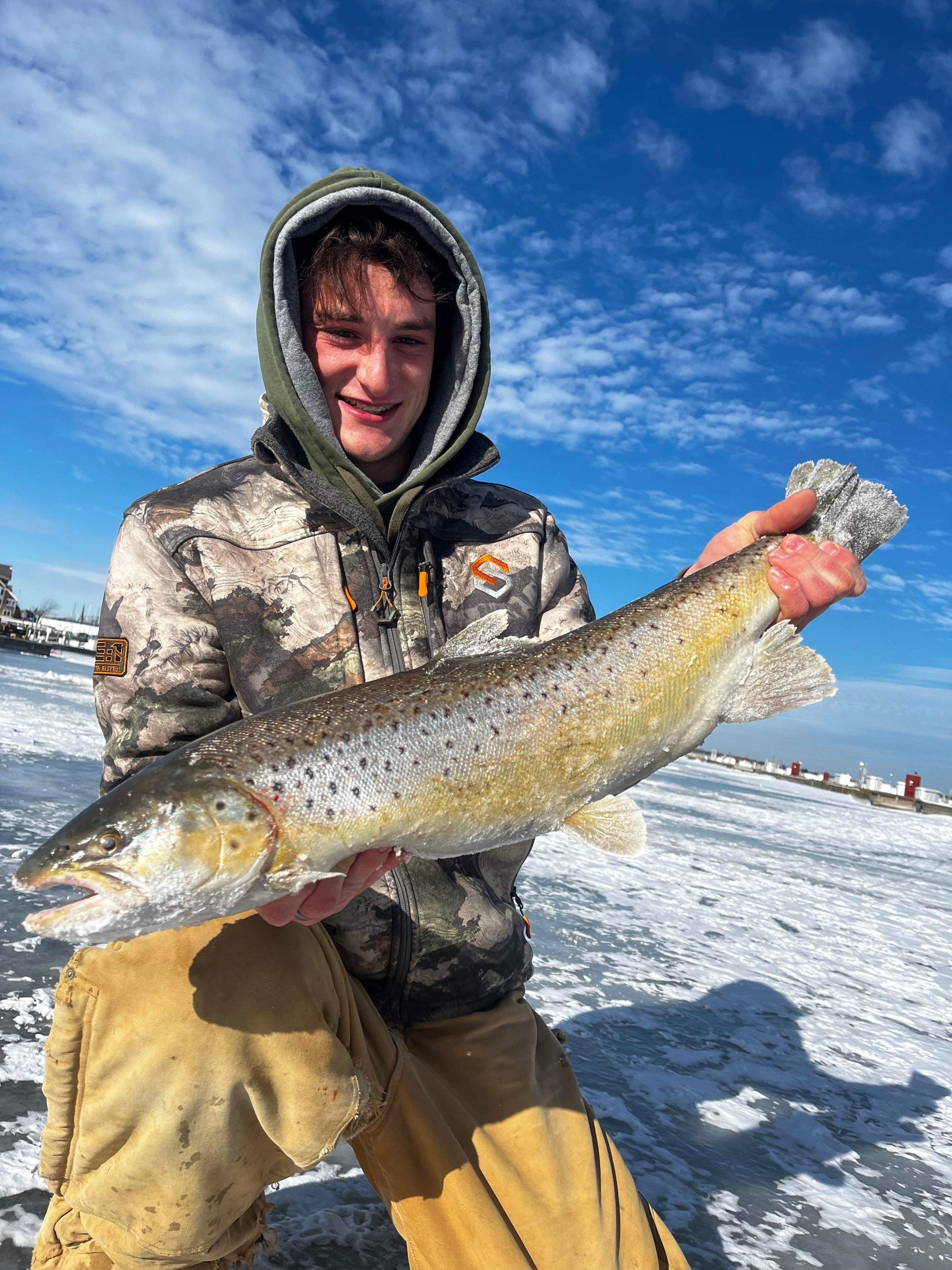 Trout held outdoors with neon green speckled tube jig in mouth