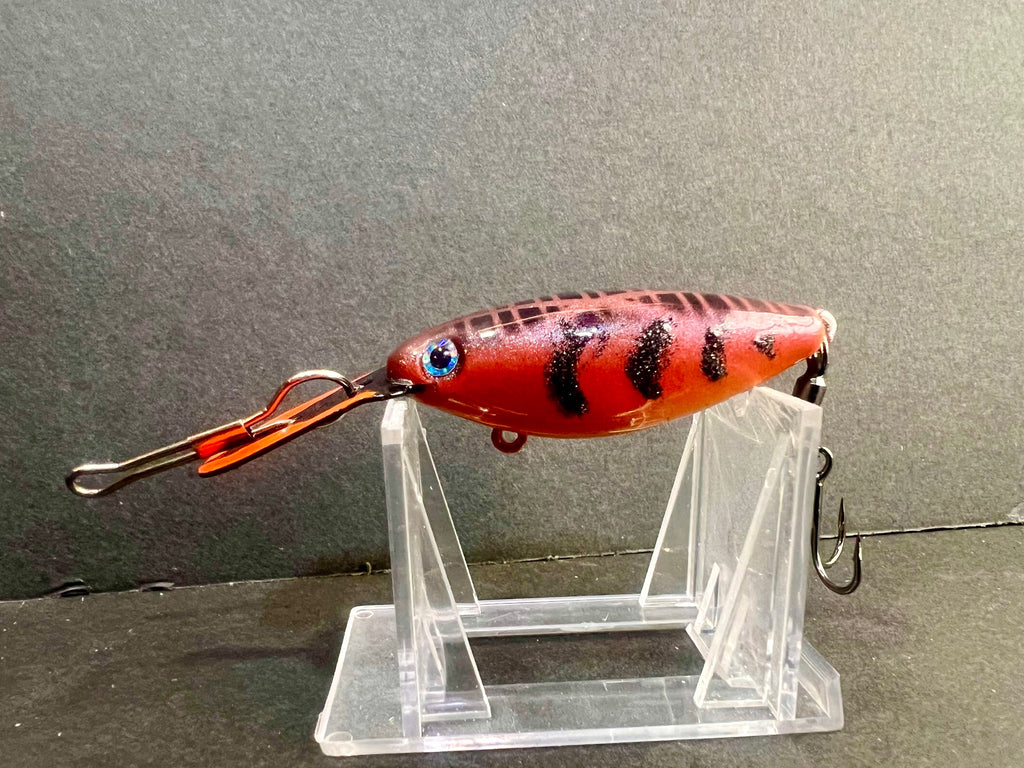 Red-orange rattling trolling plug with dark spots, blue eye, and metal treble hook