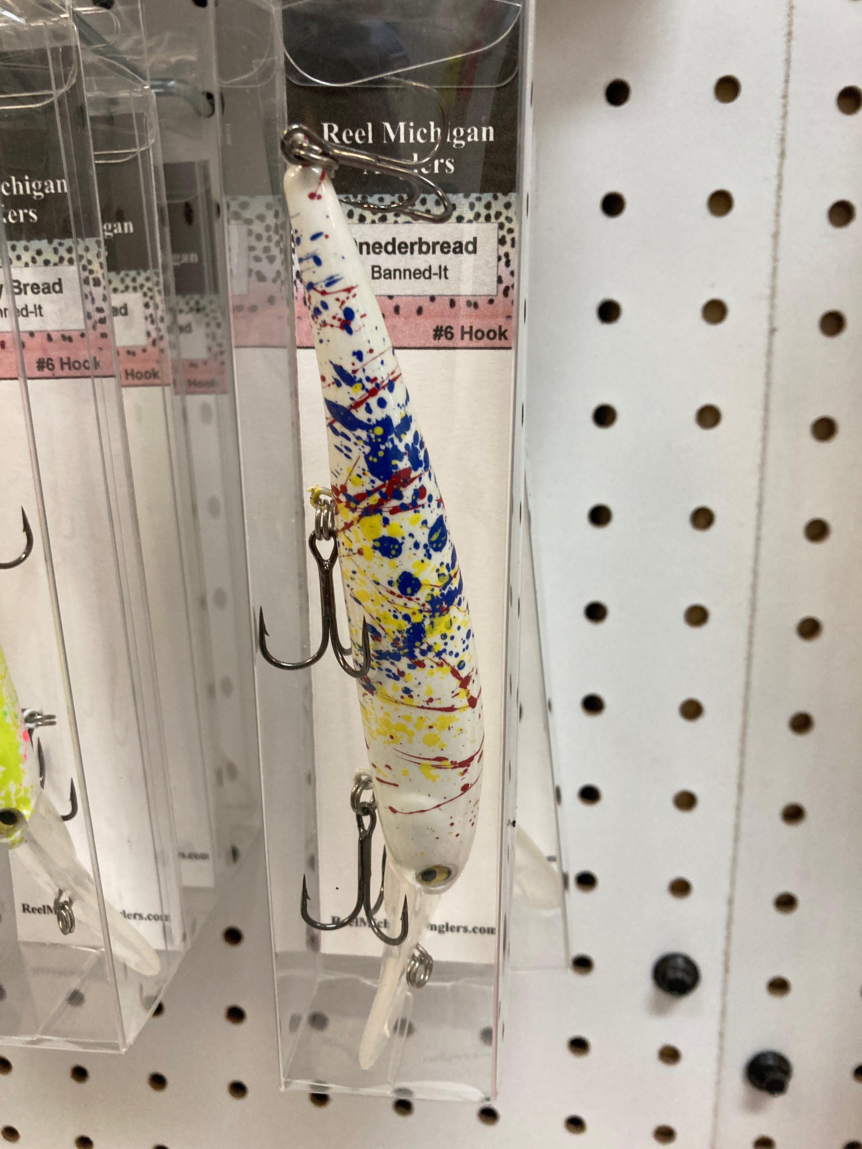 Fishing lure with white body and blue-yellow splatter, hanging treble hook