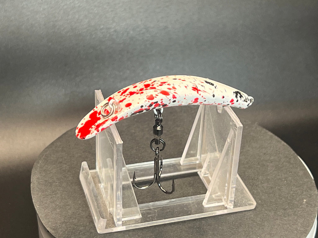 Dexter UV Glow Swiftfish lure on clear display stand, red and white speckled