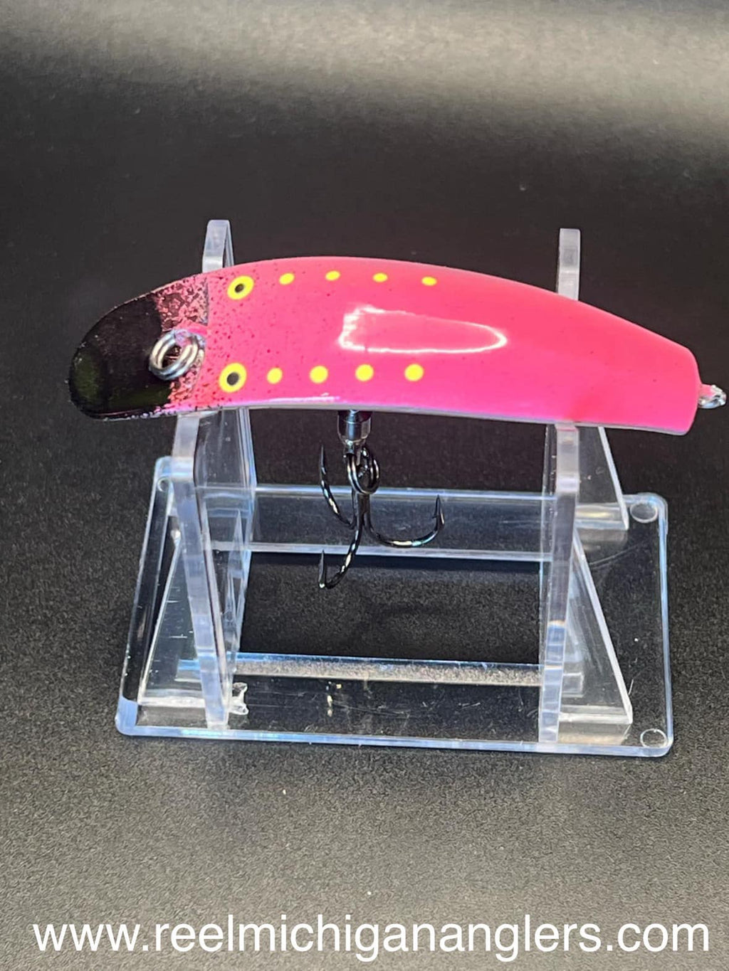Pink fishing lure with yellow polka dots and black underside, metal ring and treble hook