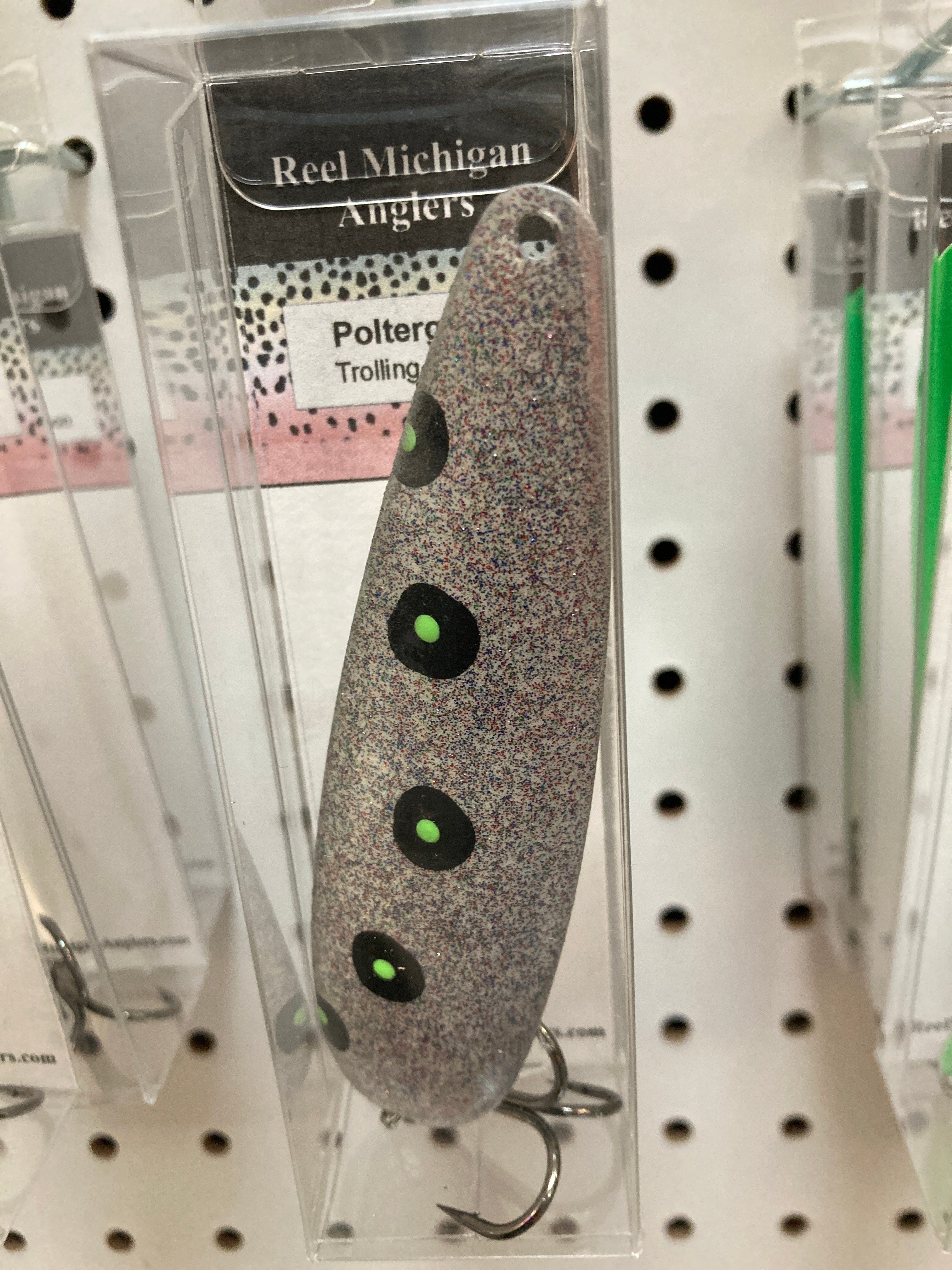 Speckled gray trolling spoon with neon green dot eyes, in retail blister pack
