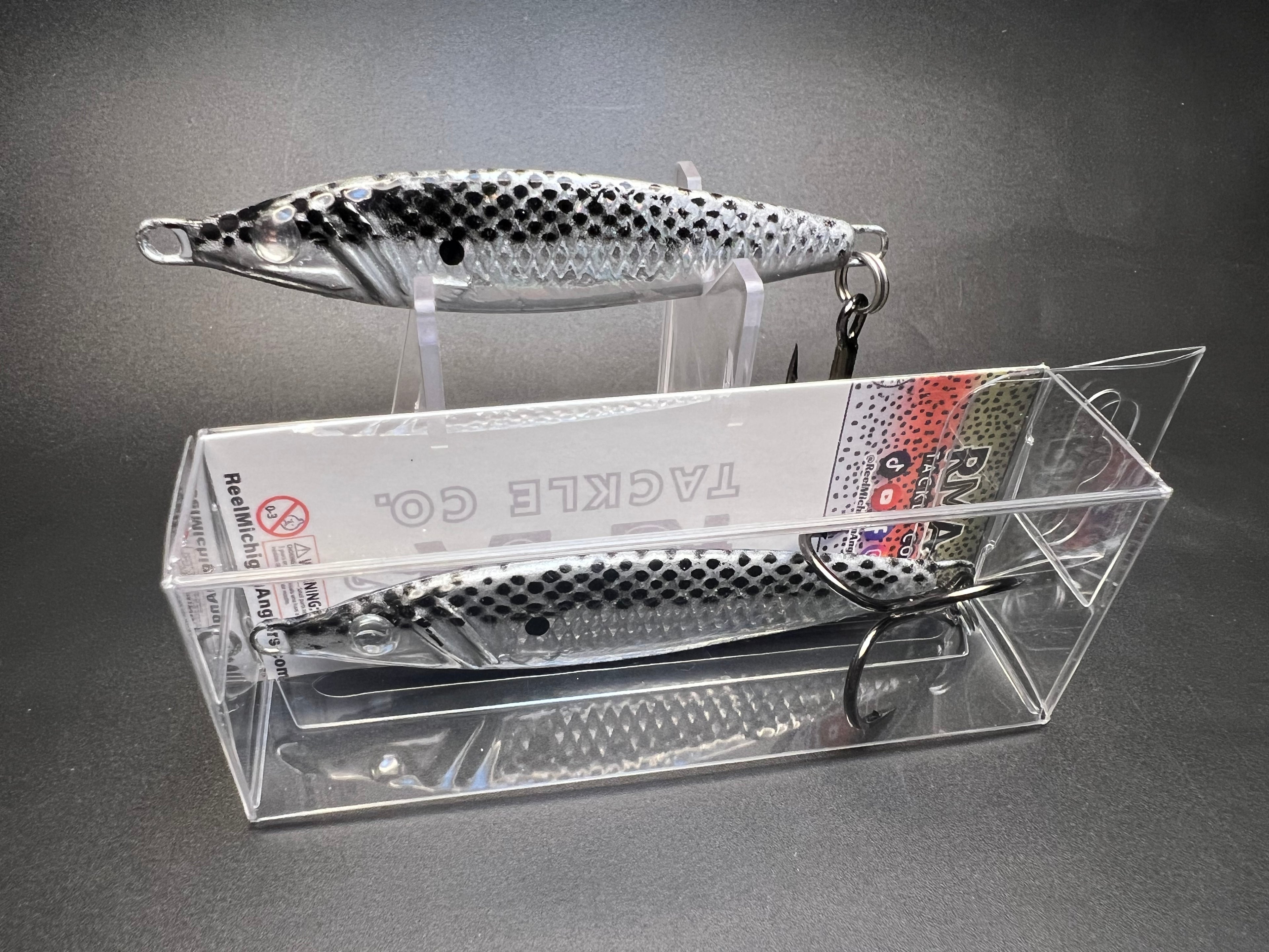 Metal jigging spoon fishing lure, silver with black dots, single treble hook in packaging