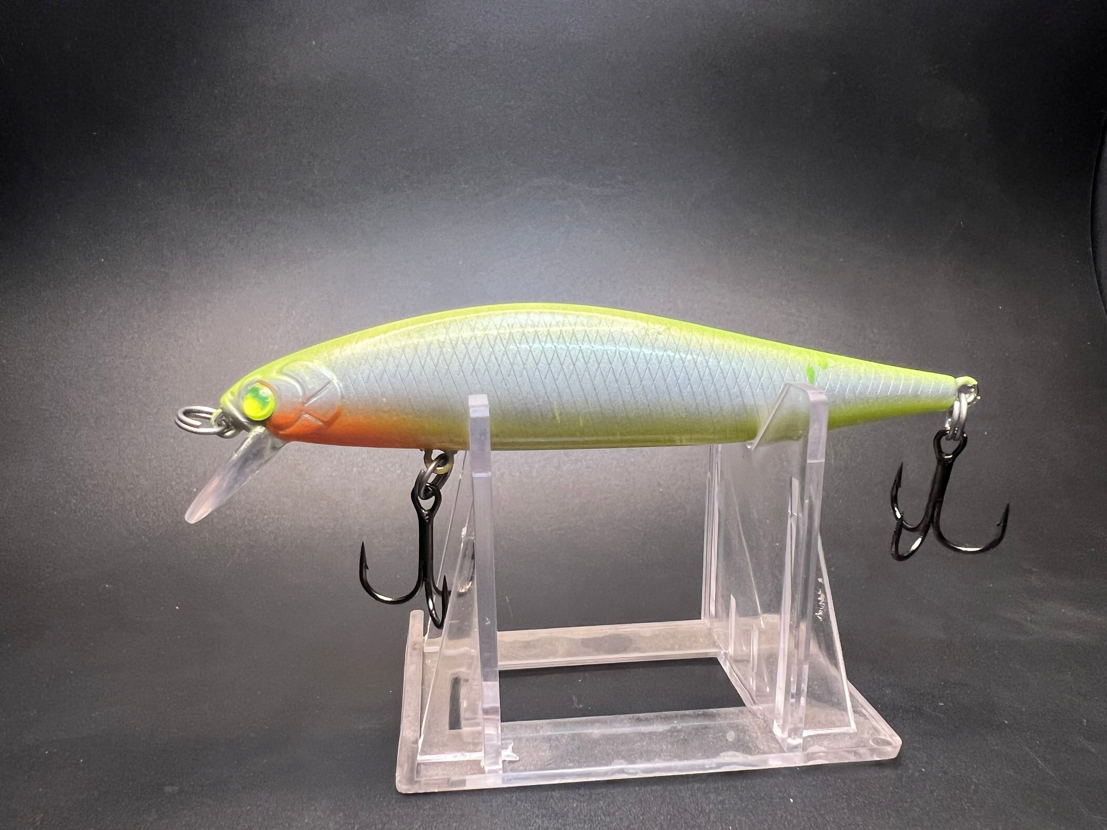 Jerkbait fishing lure in lime green and orange with three treble hooks