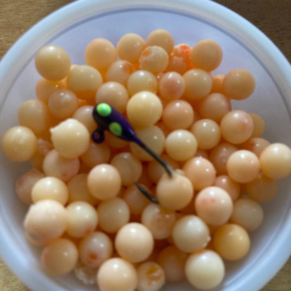 Hookable loose cured coho salmon eggs in a bowl, pale orange-yellow beads with lure