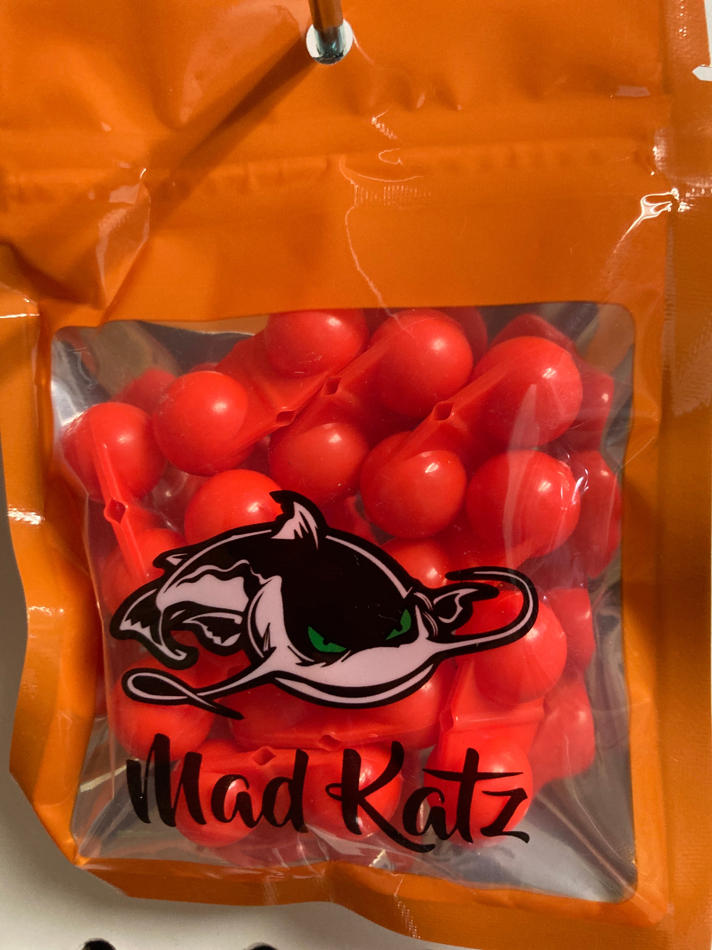 Red cat rattle toy with Mad Katz logo, orange pouch filled with rattle balls