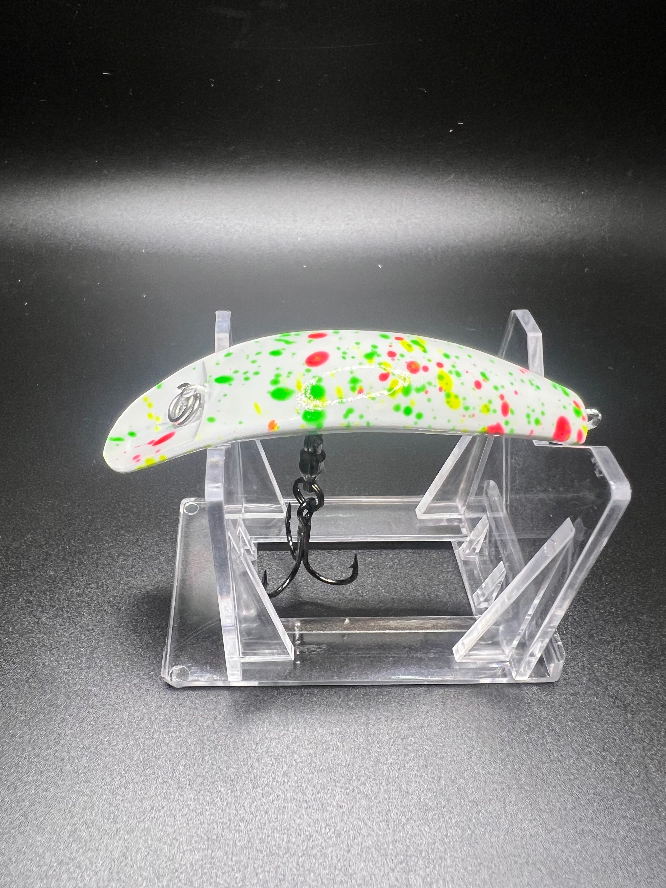 Swiftfish lure with white body and colorful speckles, on clear display stand