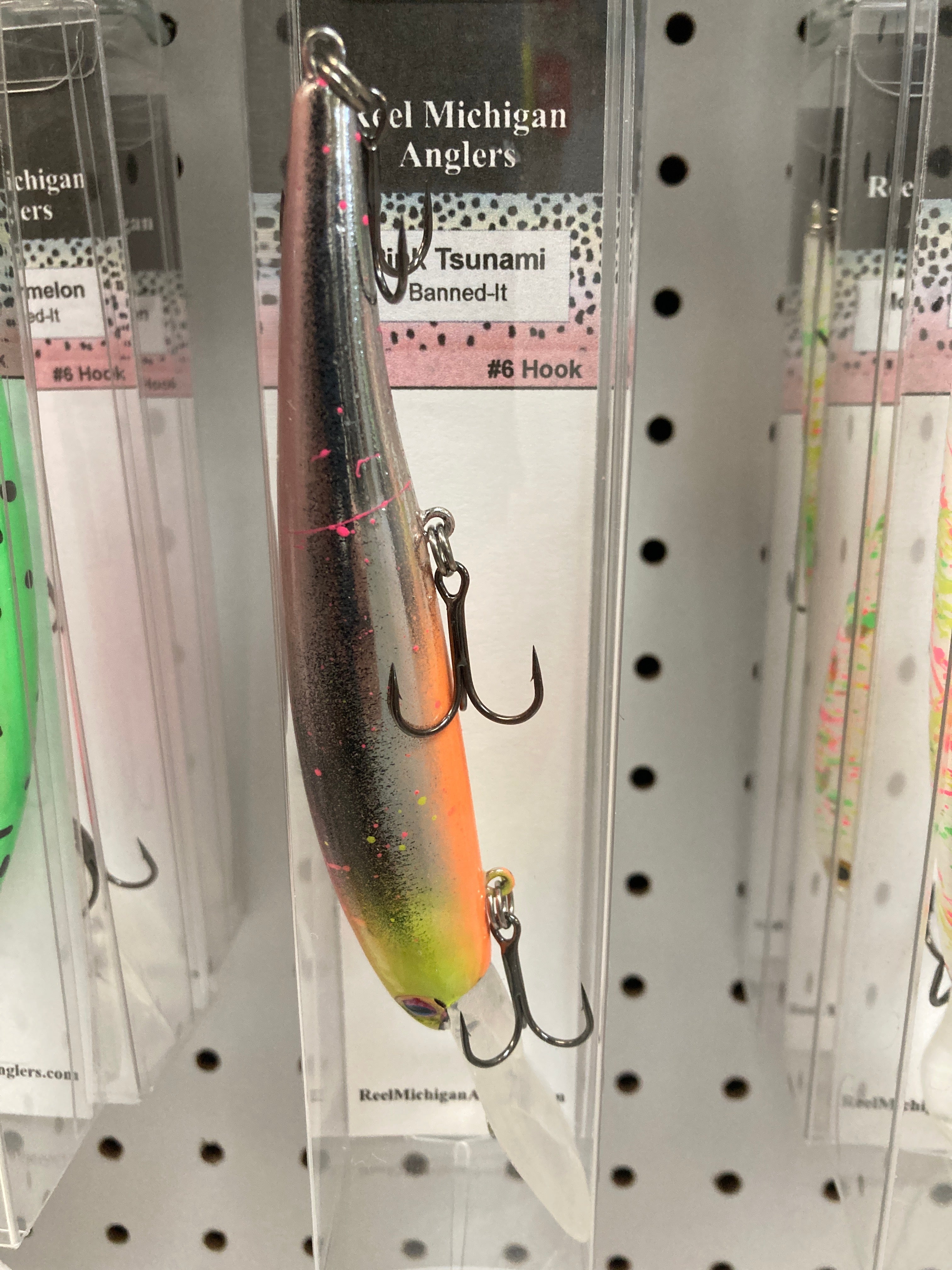 Fishing lure with dark speckled body and orange underside, double treble hook