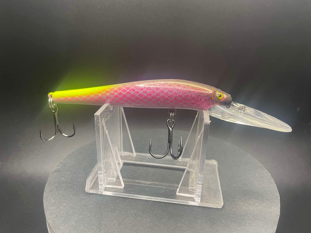 Pink-and-clear fishing lure with yellow UV glow, metal treble hooks on body
