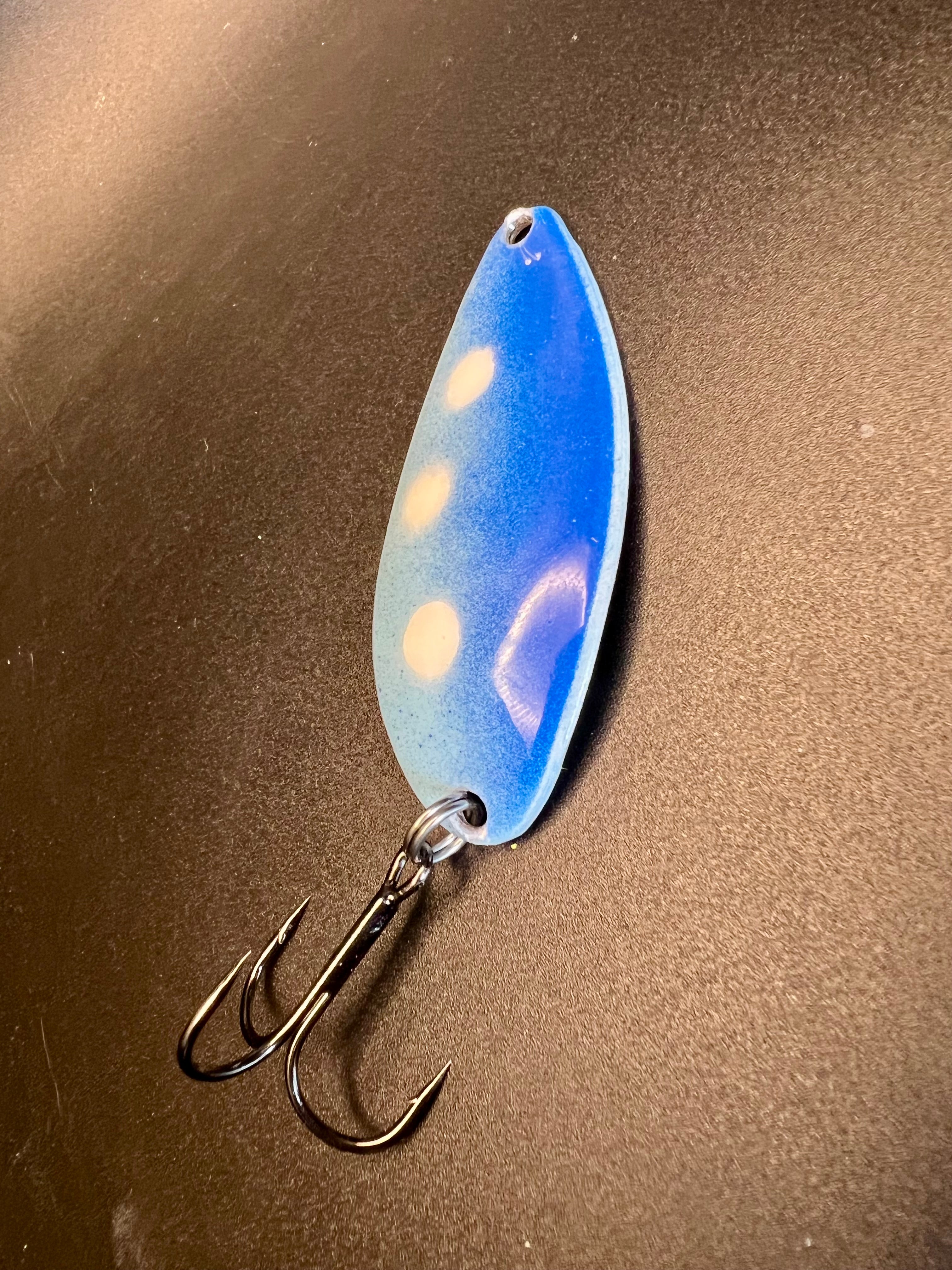 Blue spoon-style fishing lure with white spots and two treble hooks