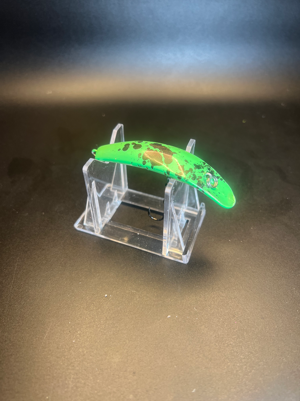 Green UV Swiftfish lure on clear acrylic display stand, side view