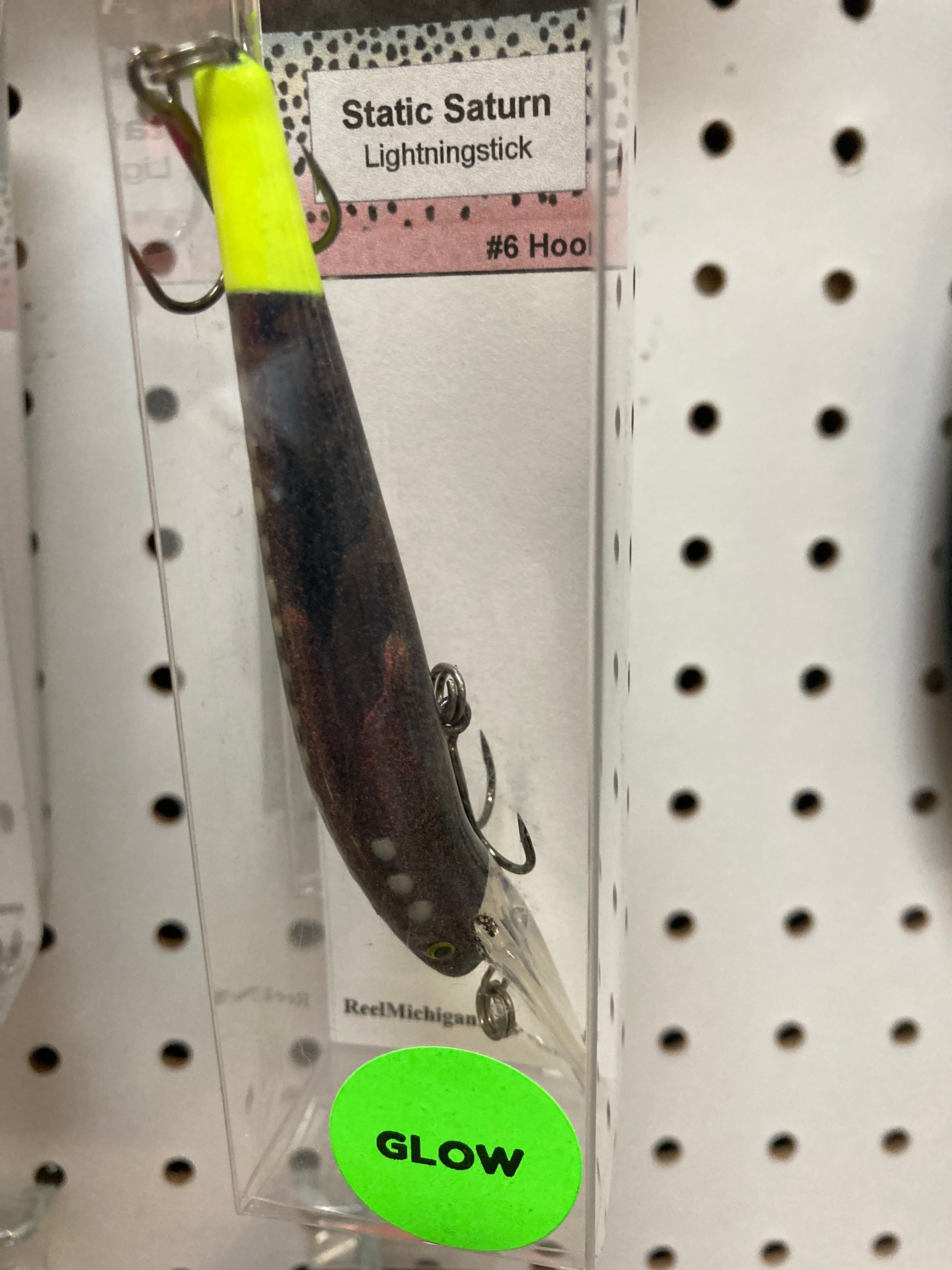 Glow fishing lure lightning stick with black body, neon green top, and two hooks in clear pack
