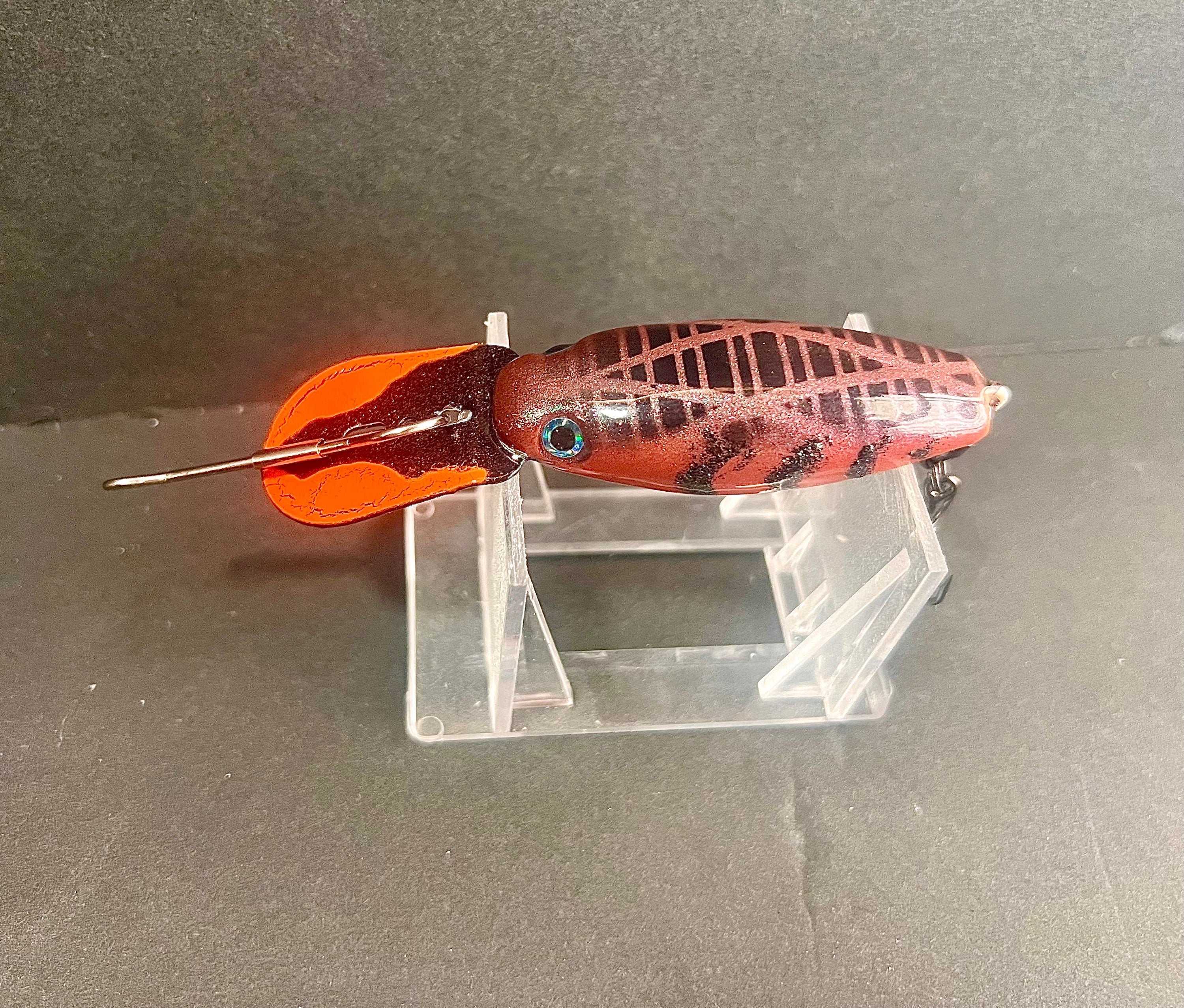 Orange and red rattling trolling plug with green-blue eye and treble hook