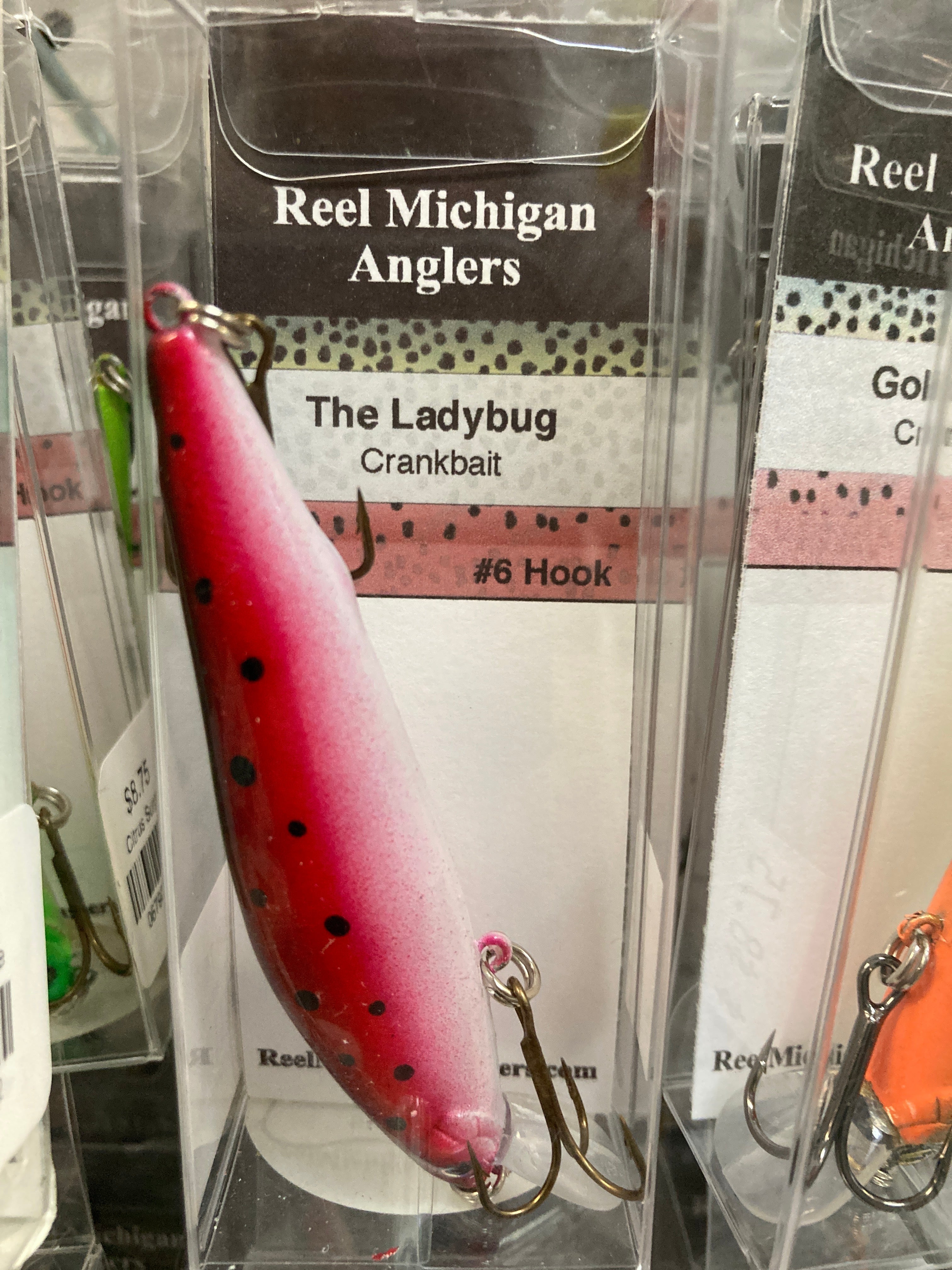 Fishing lure with red ladybug pattern, black spots and treble hook