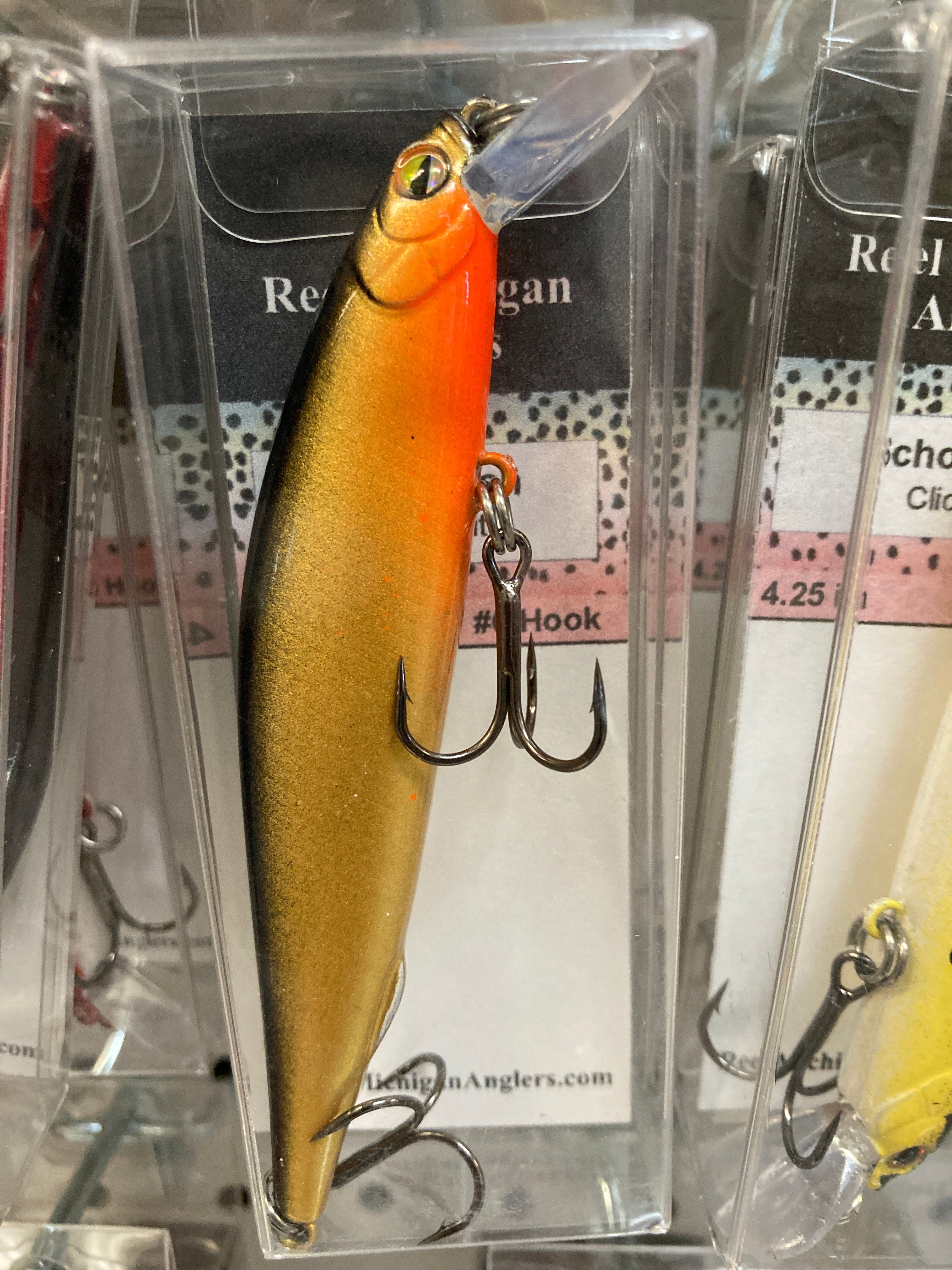 Gold fishing lure with dark facial markings, treble hooks, 4.25 in.