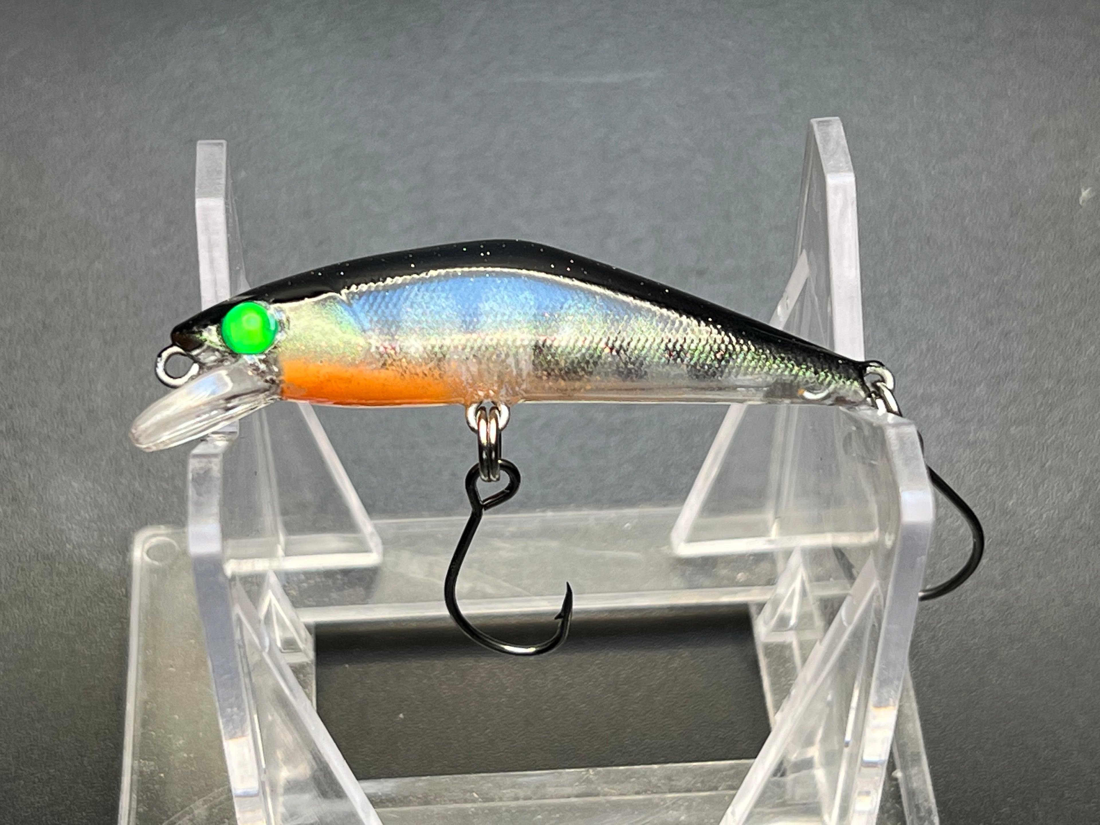 Micro sinking jerkbait lure with blue-silver body, orange belly, green eye, treble hook