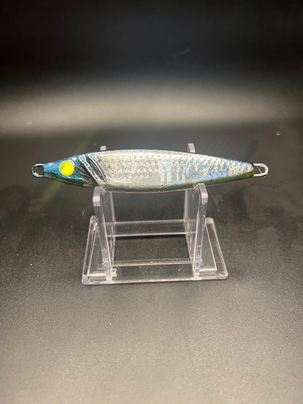 UV 2 oz jigging spoon with silver body, green-yellow eye, and treble hook