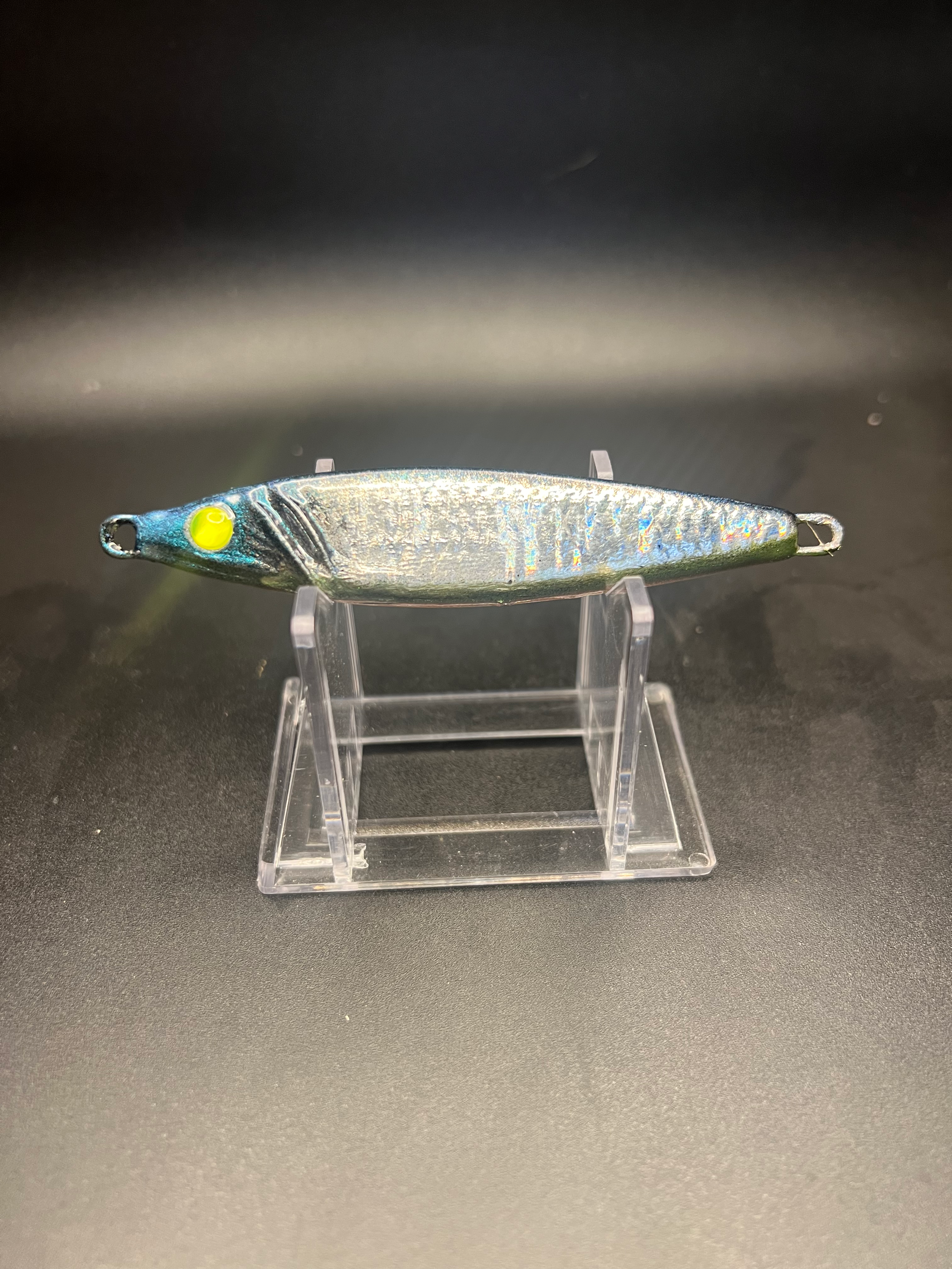 UV 2 oz jigging spoon with silver body, green-yellow eye, and treble hook
