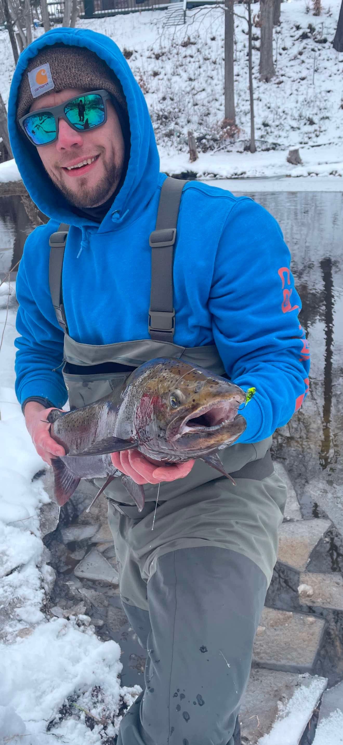 Trout in snow with neon green speckled tube jig near mouth