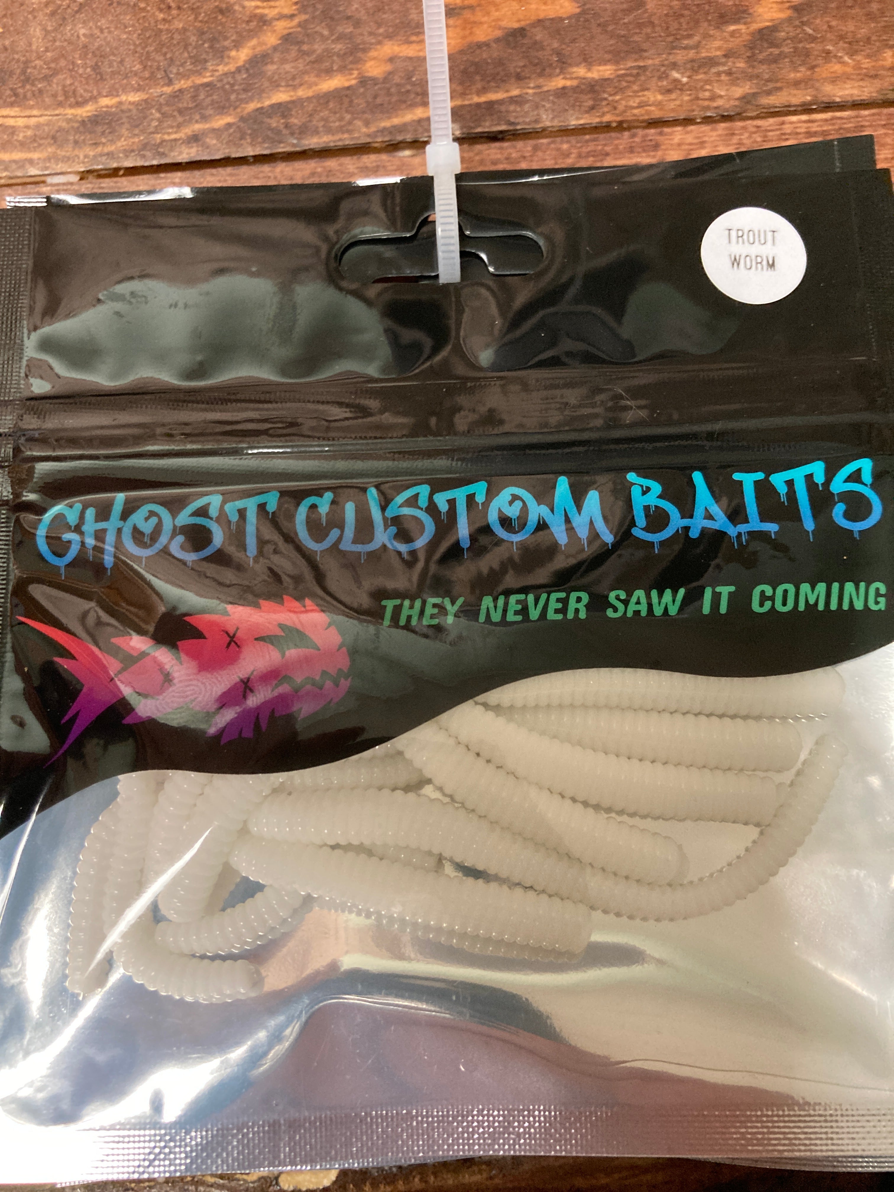 Cream custom worm bait with segmented ridges, laid in a clear package