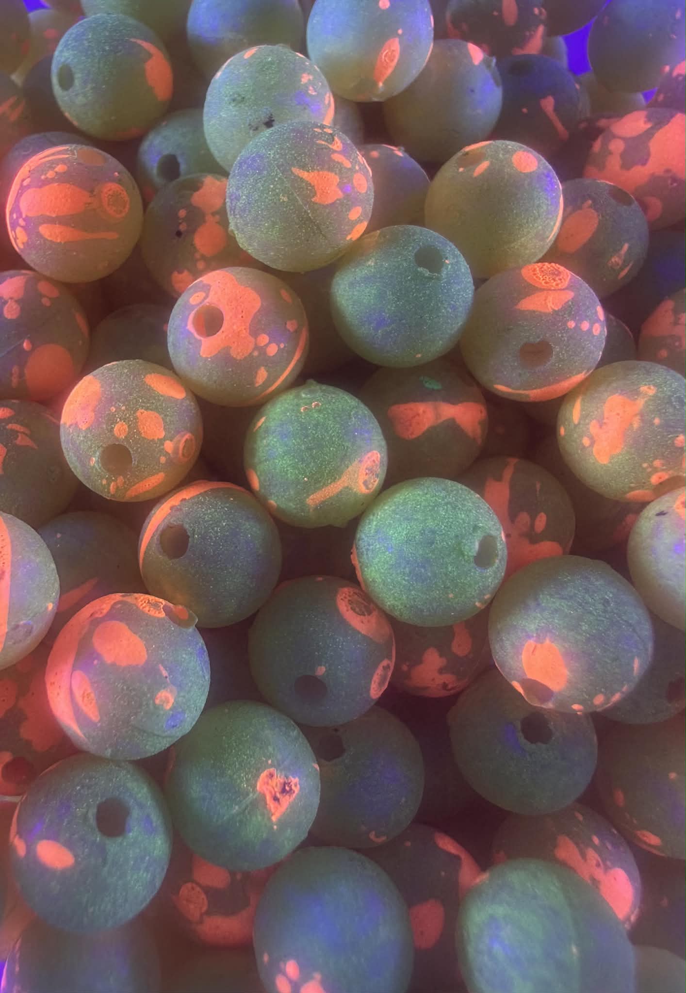 UV glow plastic fishing beads, iridescent blue-green with red/orange spots and holes