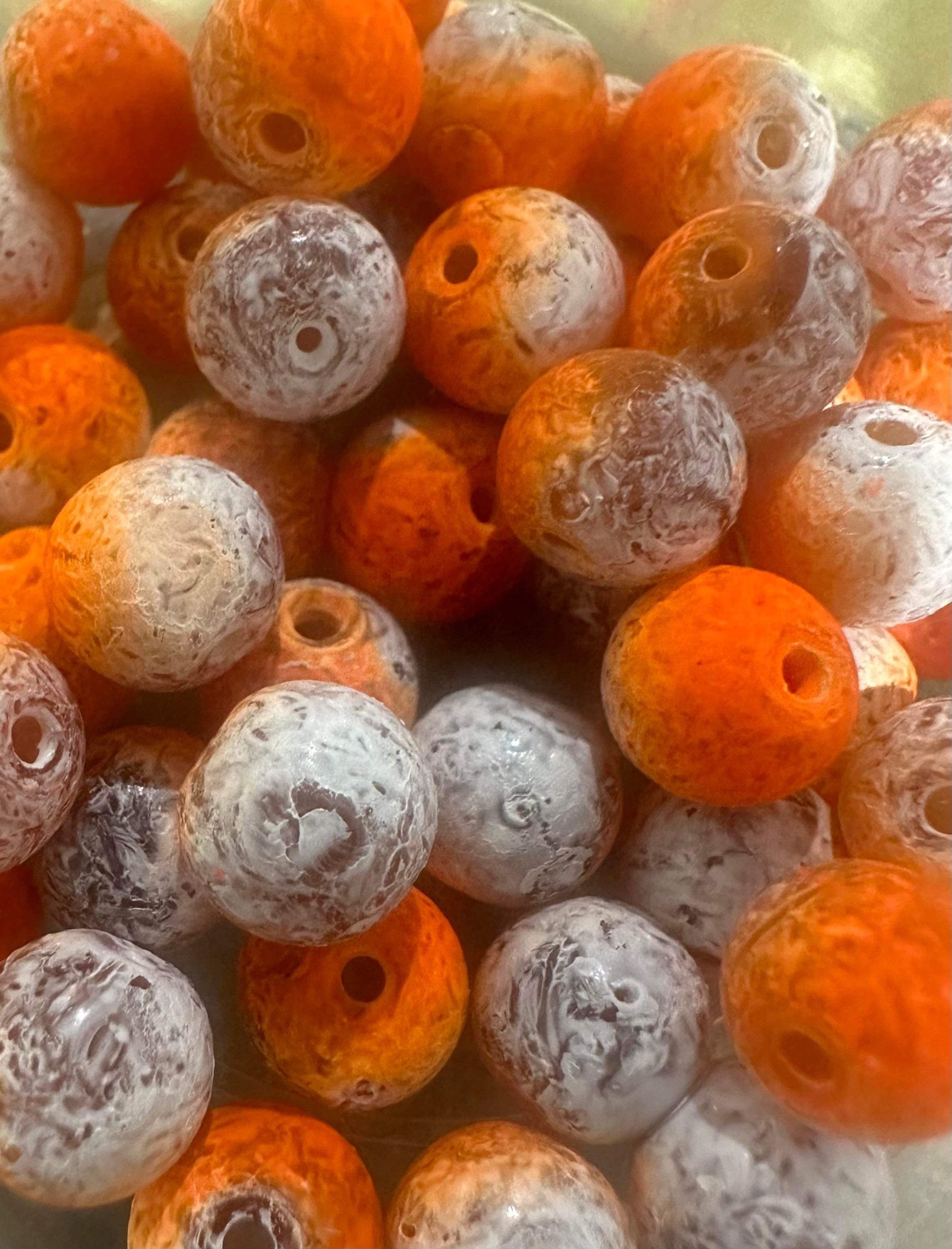 Orange and white glass fishing beads with central holes, tightly packed