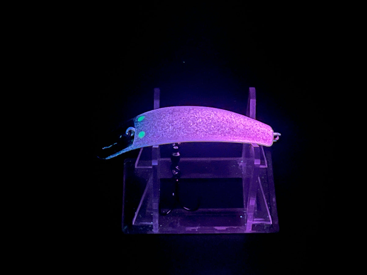 Purple glowing fishing lure with wide body and two treble hooks
