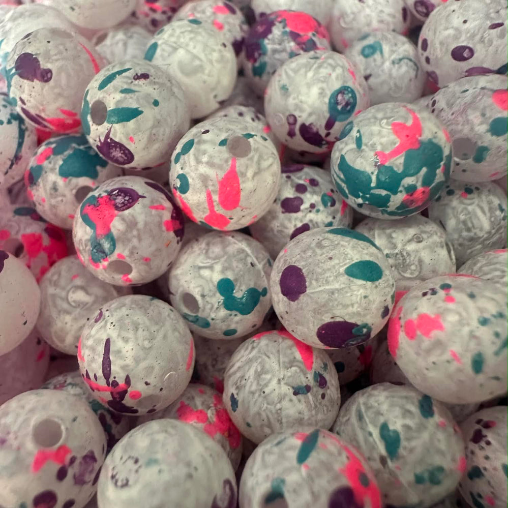 Plastic fishing beads, white with teal, purple, and pink speckle patterns