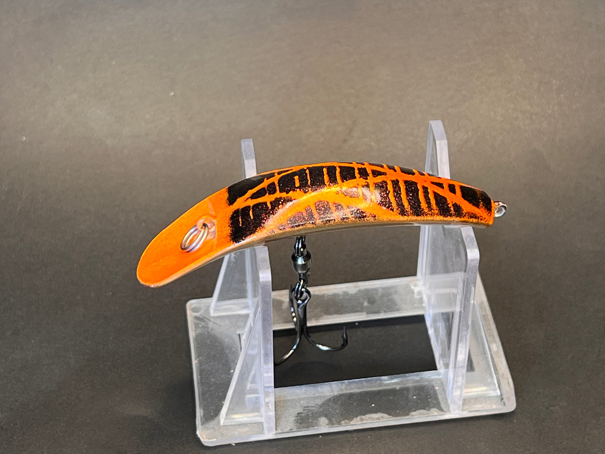 Orange and black striped fishing lure with curved bill and treble hook on stand
