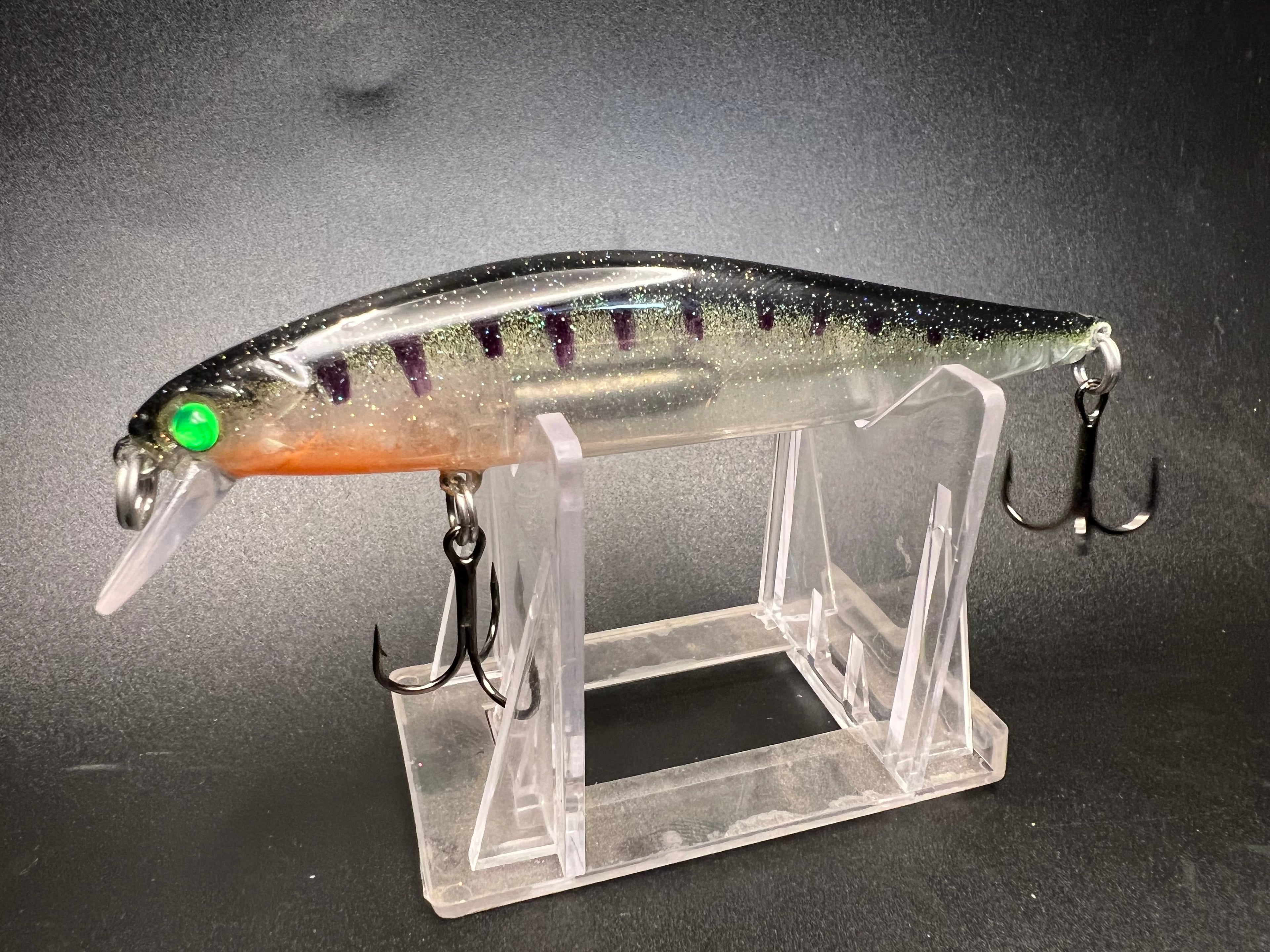 The Perchinator Clickbait UV jerk bait, clear body with purple stripes and green head