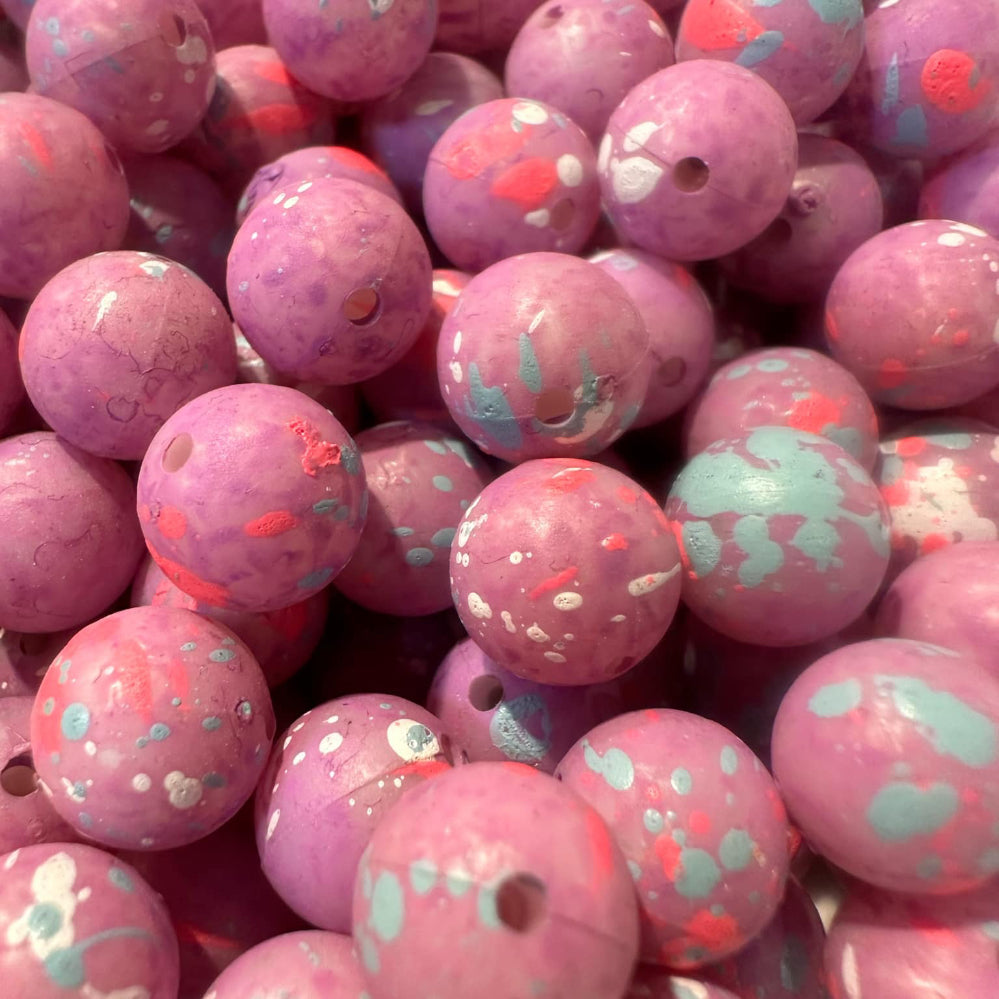 Pink UV glow fishing beads with speckled teal and red patterns