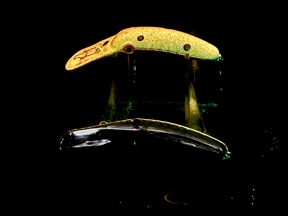 Glow fishing plug lure, gold-orange body with dark back and metal eyelets