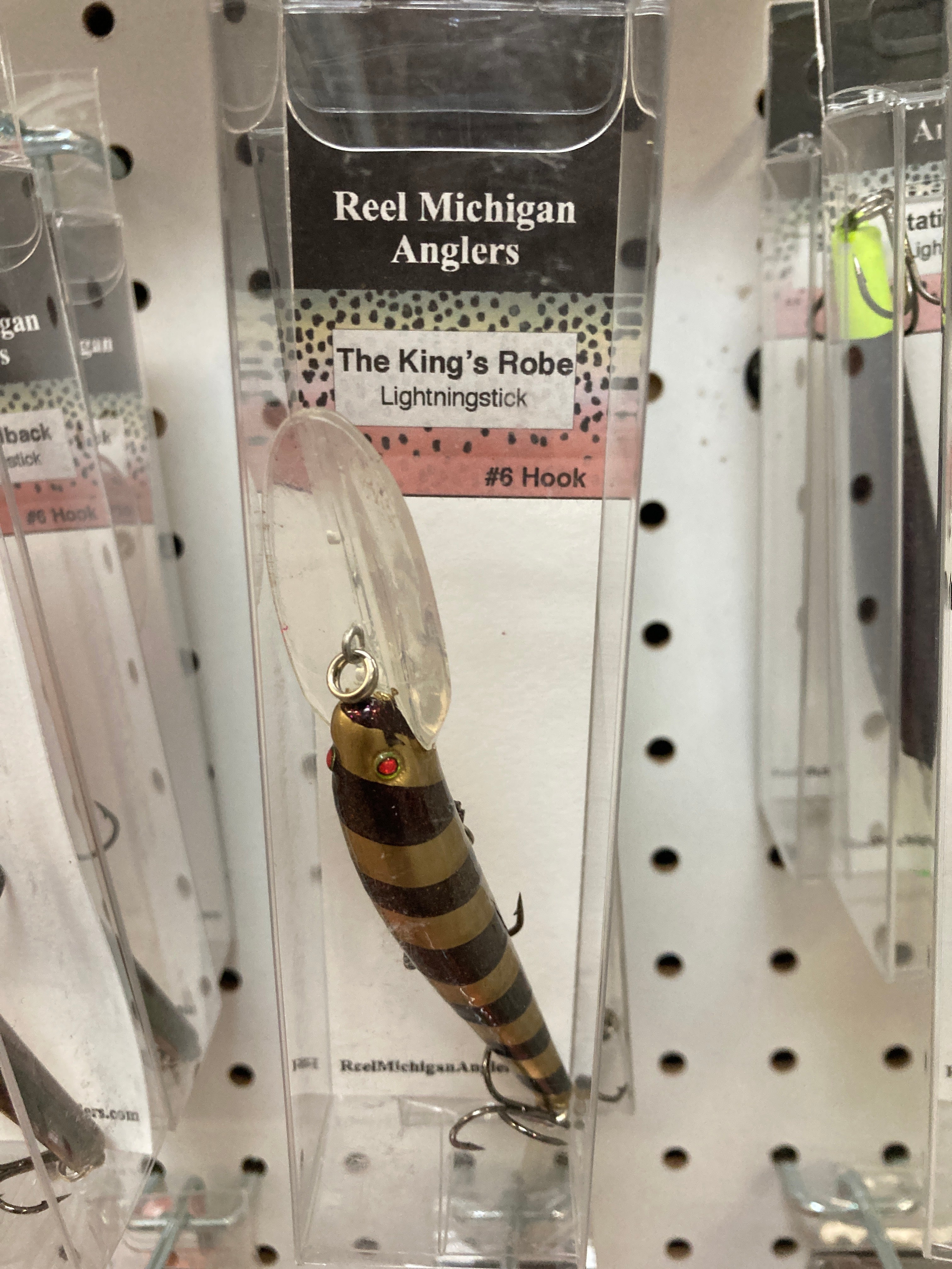 Fishing lure lightning stick with striped brown-and-gold body and two hooks in clear pack