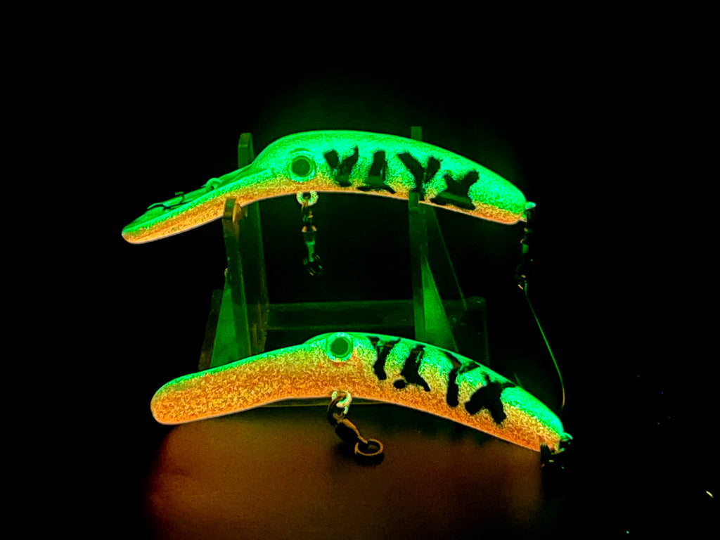Two glow fishing lure plugs, green bodies with black markings and treble hooks