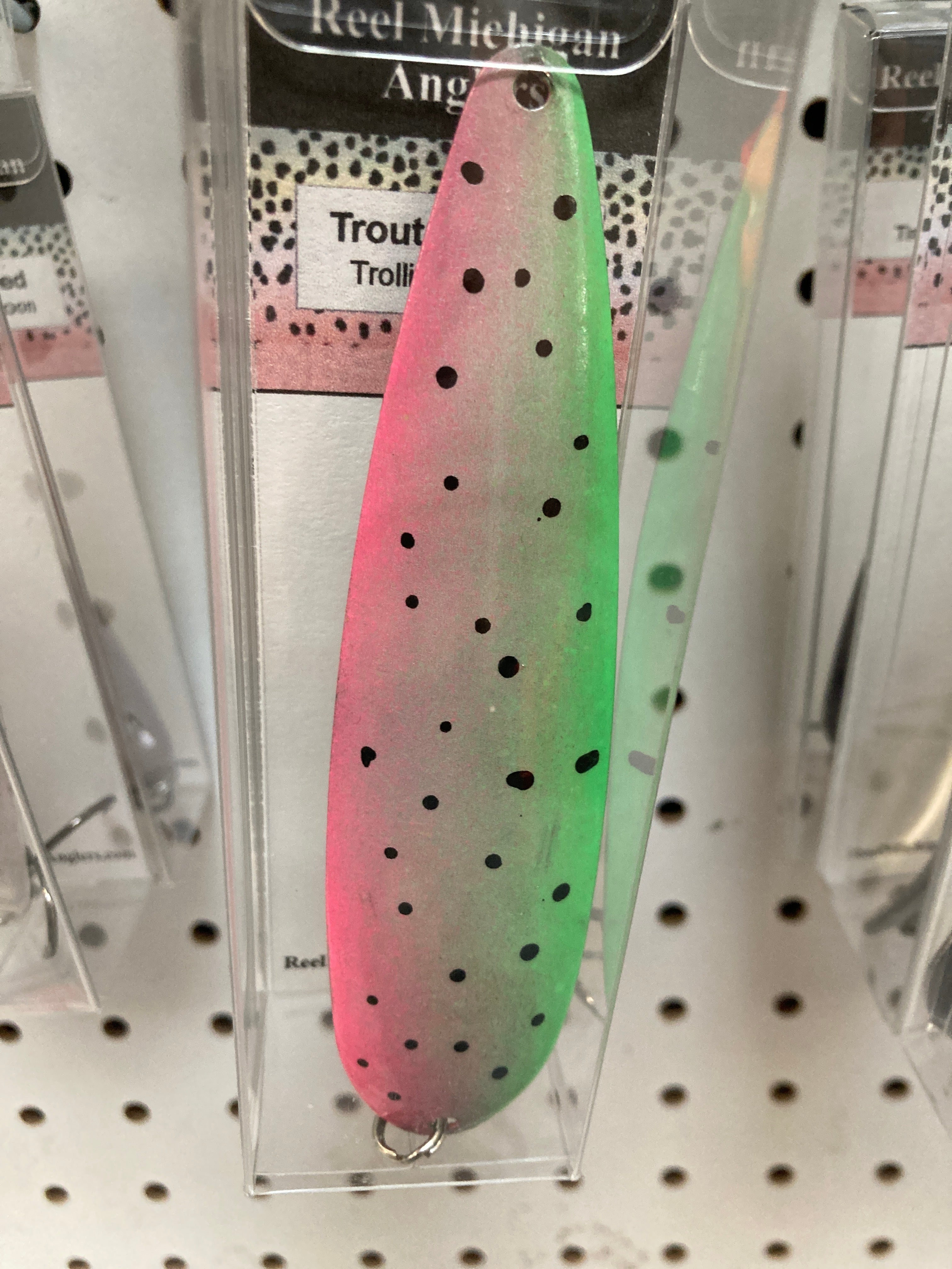 Pink and green trolling spoon with black dot pattern, in retail blister pack
