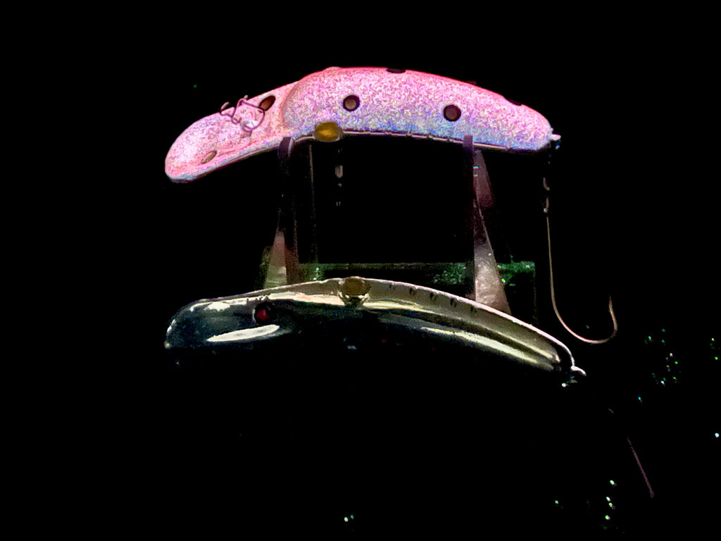 Glow fishing lure plug in pink, with treble hooks and split metal harness