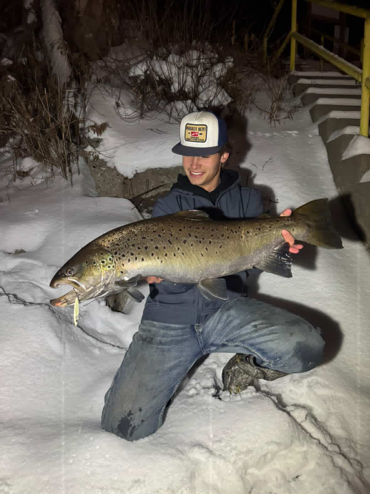 Trout holding a jigging spoon lure in its mouth, winter night fishing outdoors
