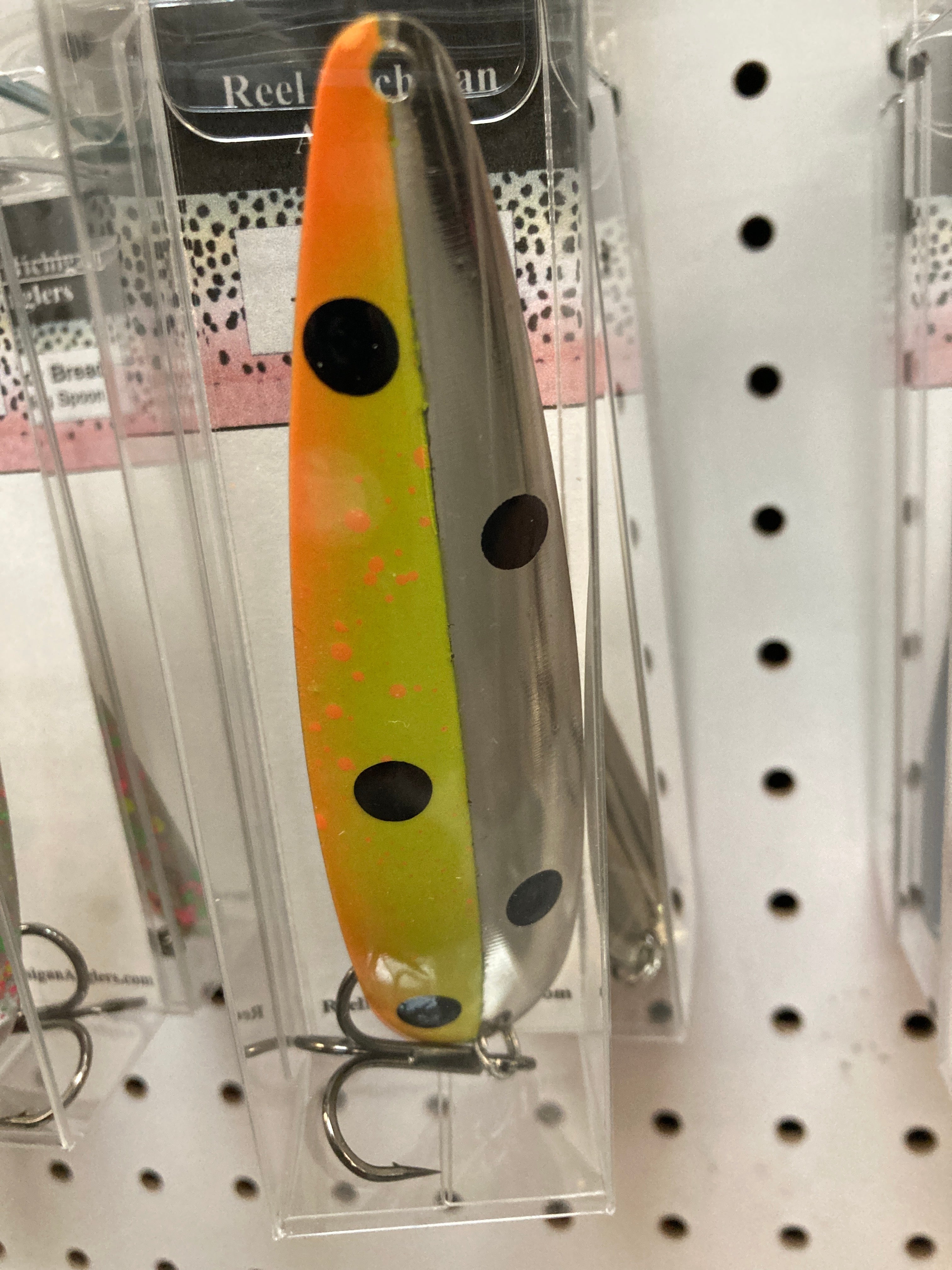 Orange and yellow trolling spoon with black and dark dot spots, in retail blister pack