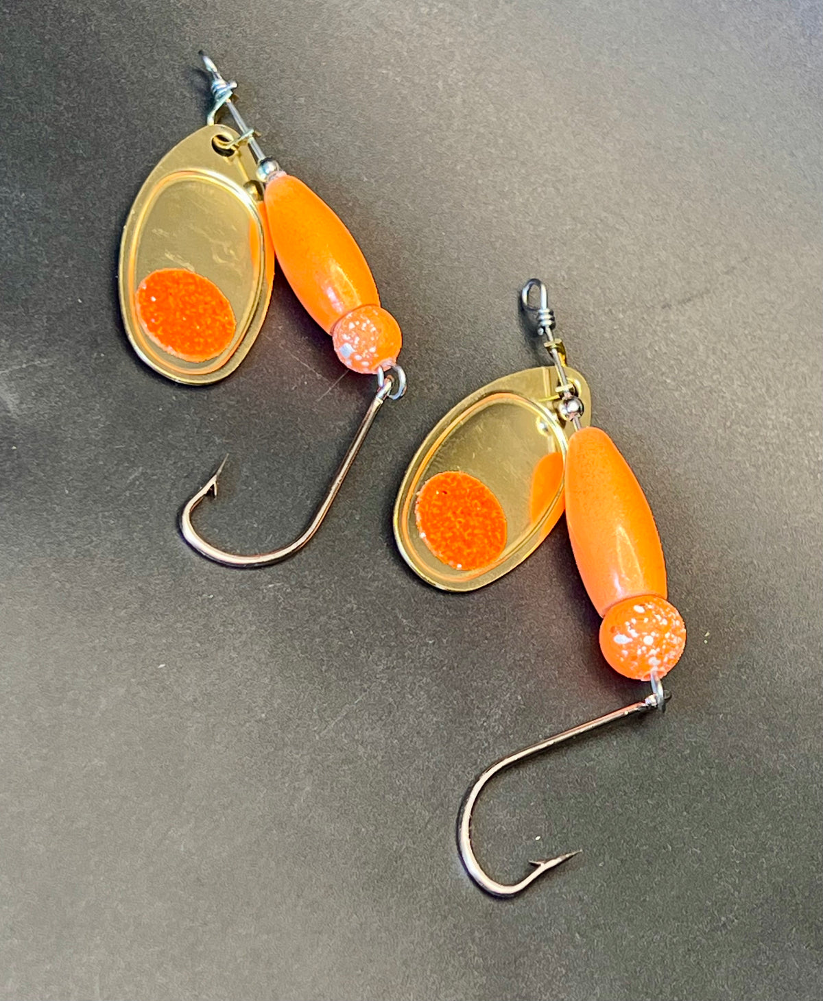 Orange inline spinner fishing lure with gold teardrop blades and treble hooks