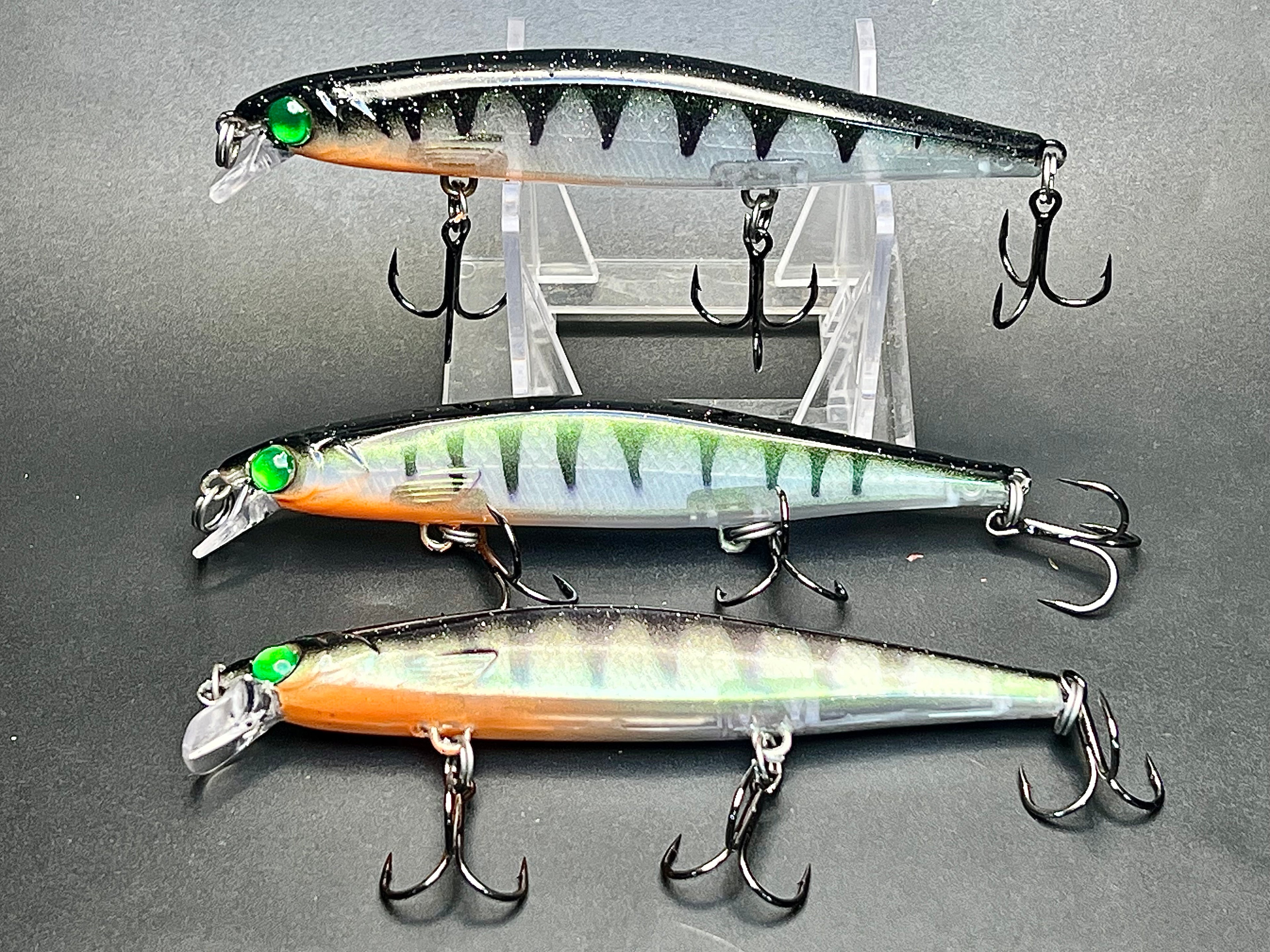 Suspending jerkbait lures with green eyes and striped, silver-blue bodies
