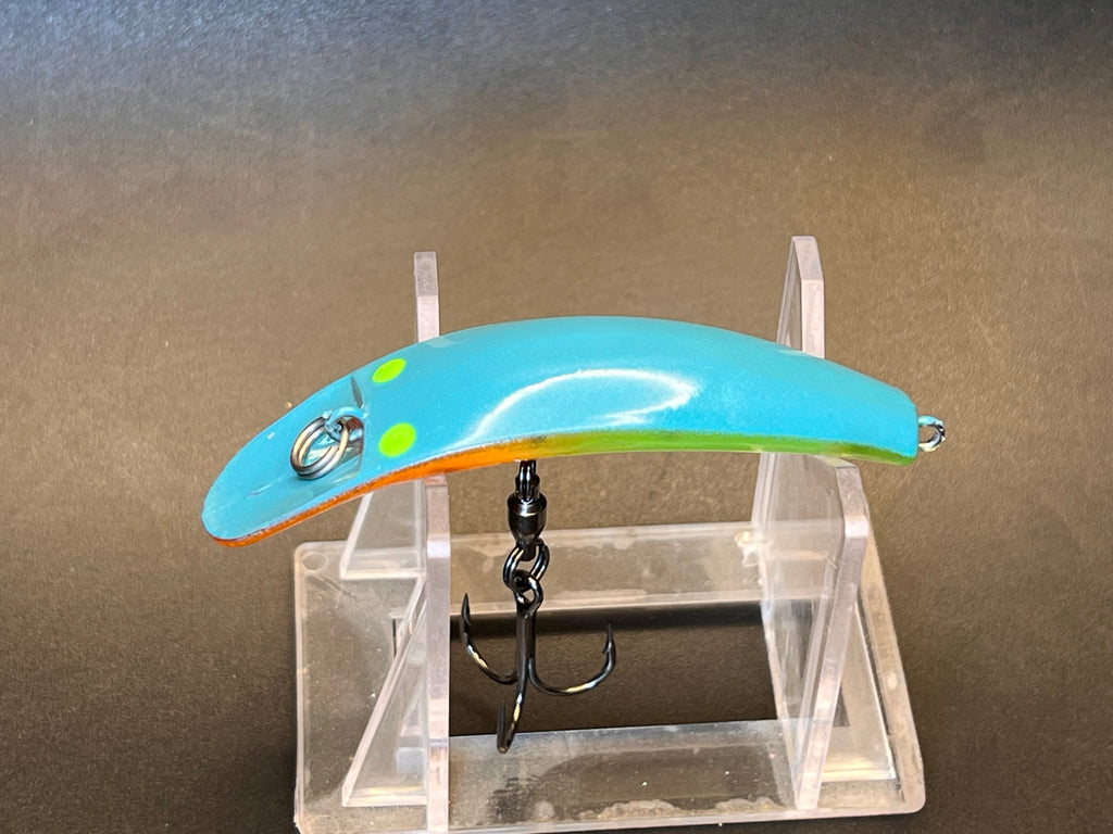 Fishing lure with blue body and green accents, single hook, in clear acrylic stand