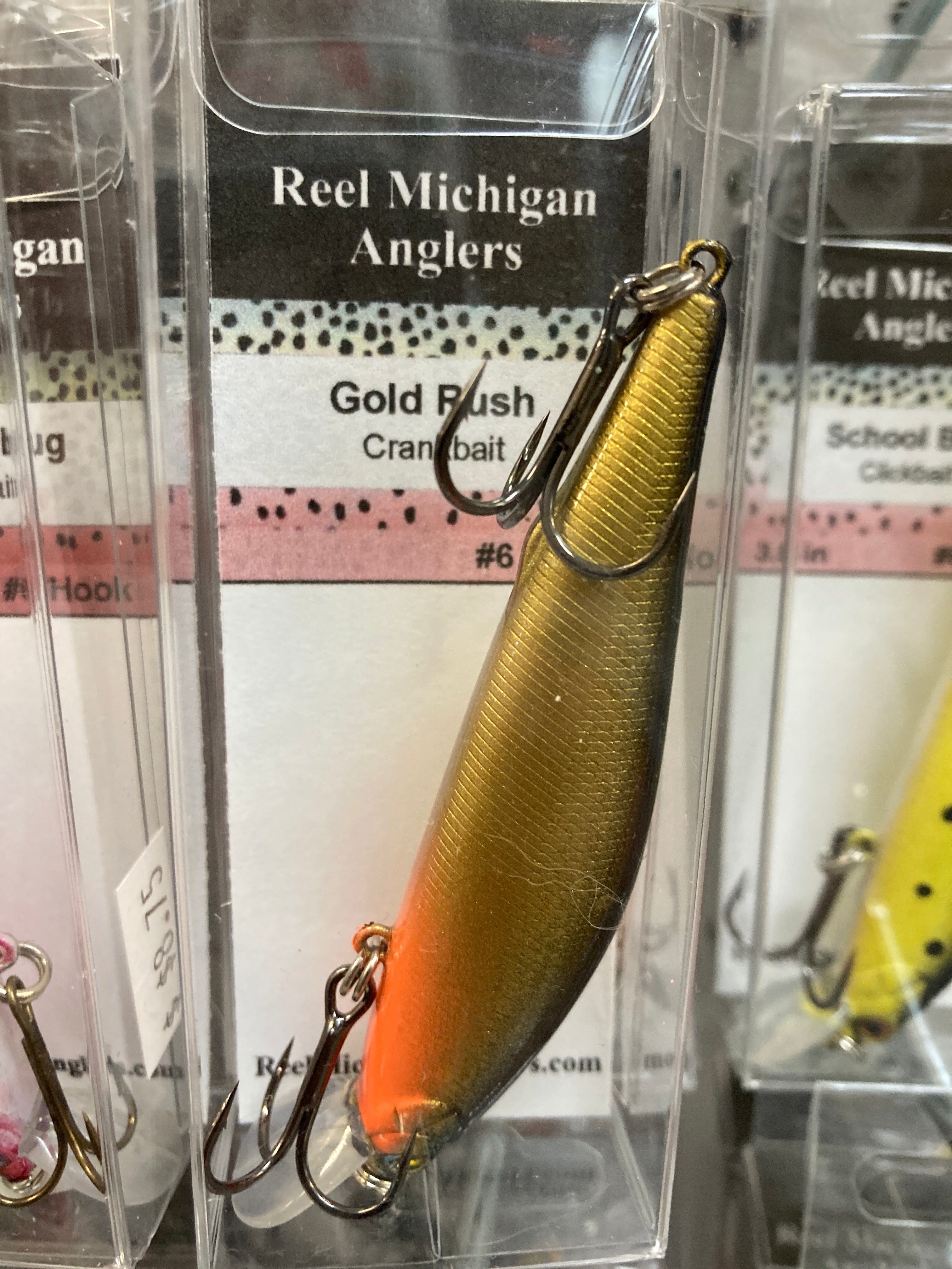 Fishing lure with gold finish and orange-red lower half, treble hook