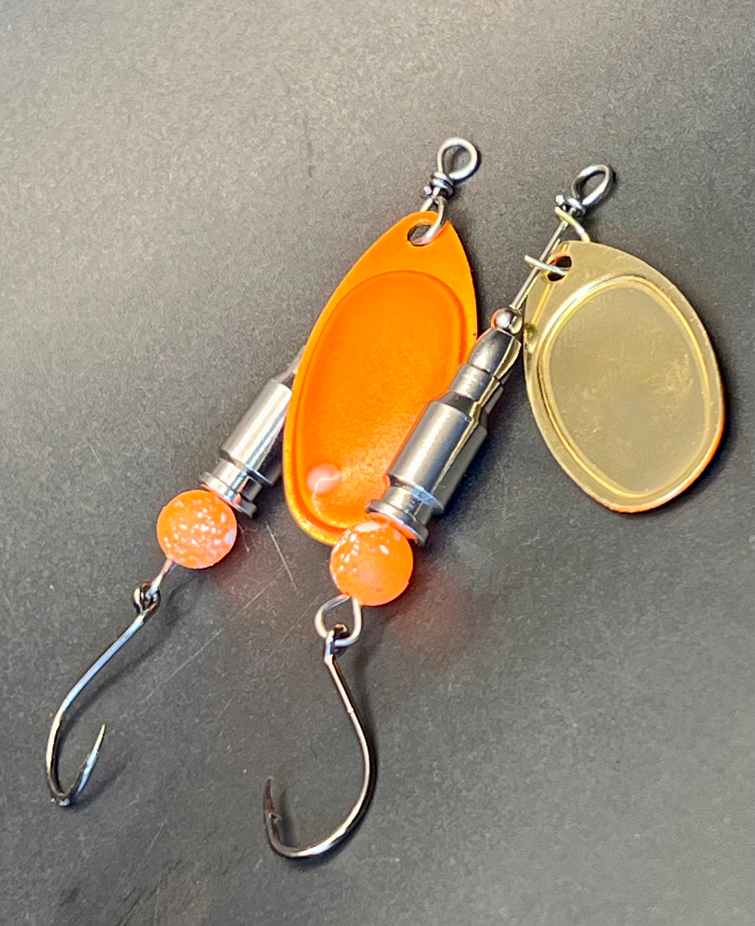 Inline spinner lure with chrome bullet body, orange glow beads, and two treble hooks