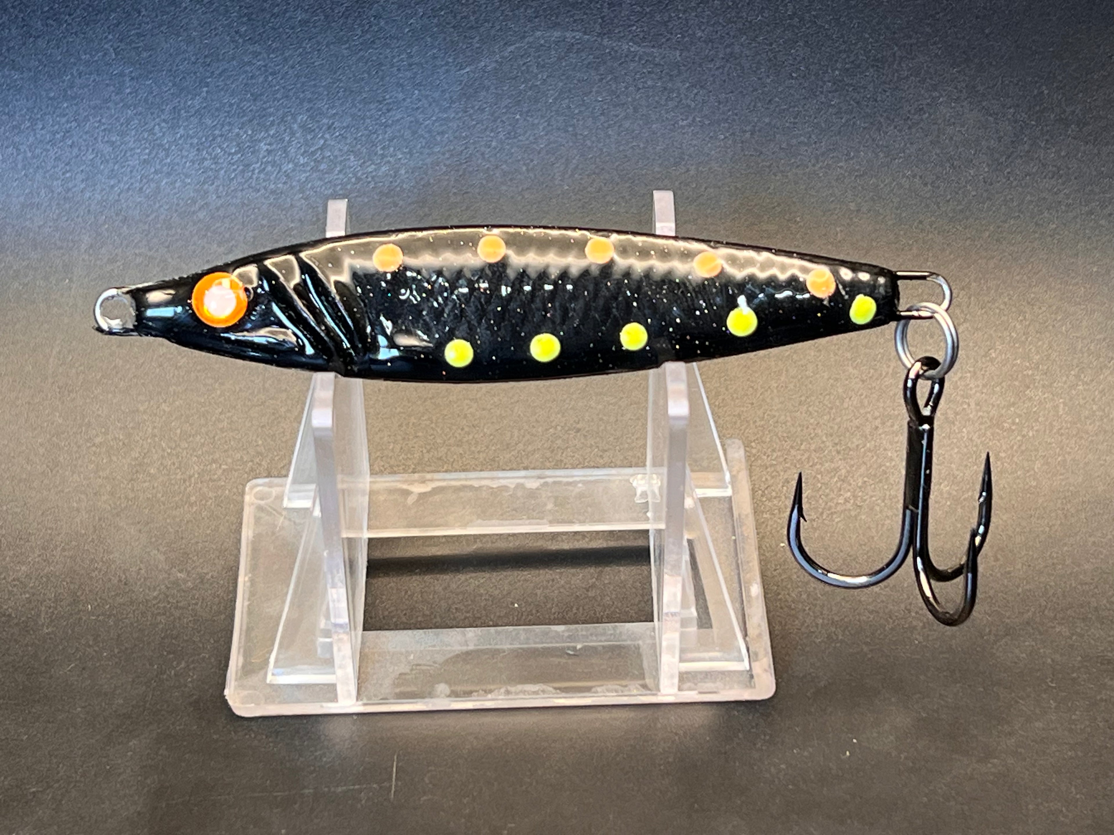 Fishing jigging spoon lure, black with yellow and orange dots, metal treble hooks
