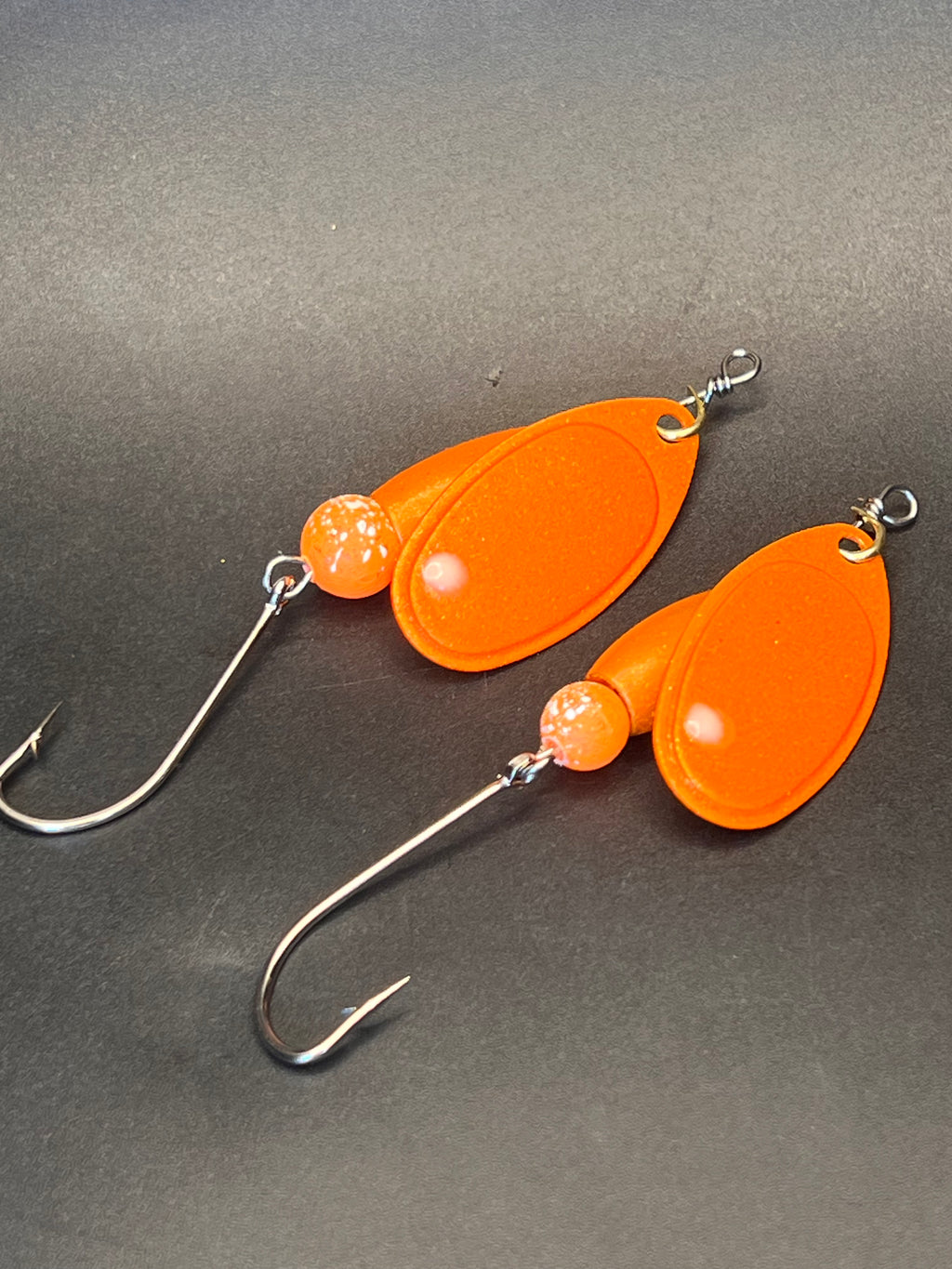 Set of two orange inline fishing spinners with teardrop blades and treble hooks