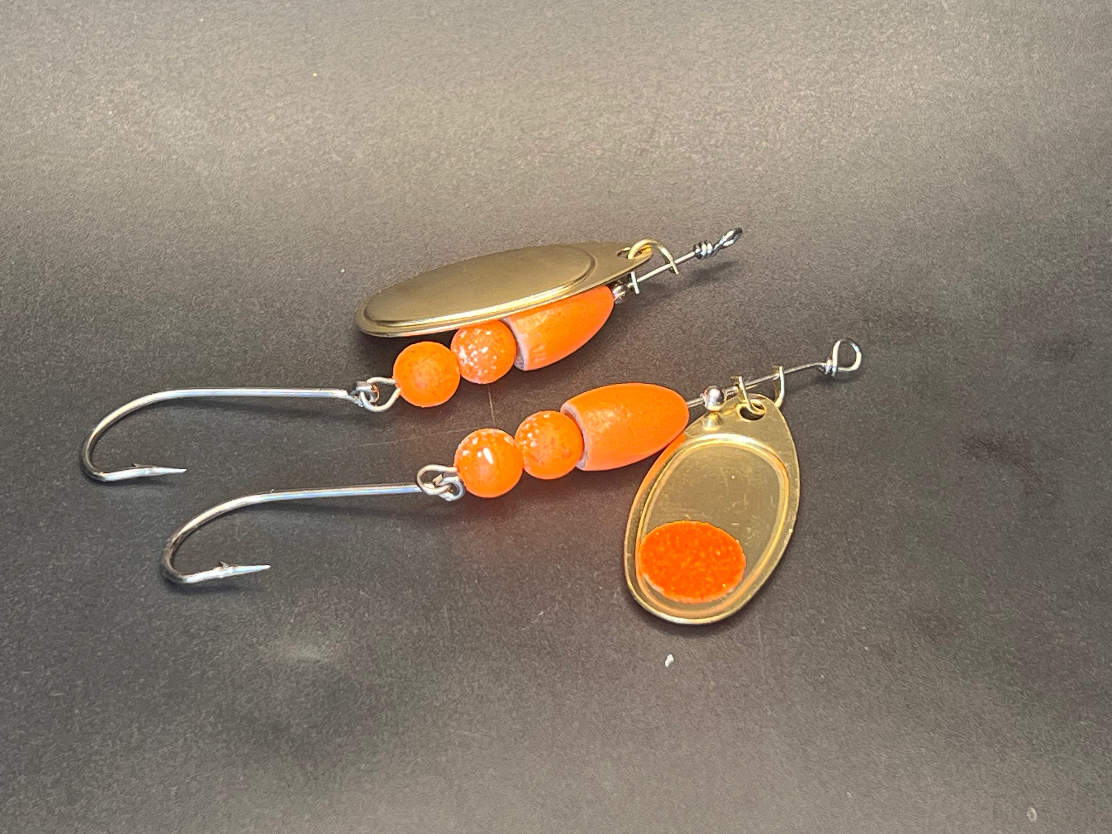 Orange inline spinner fishing lure with gold blade and treble hooks