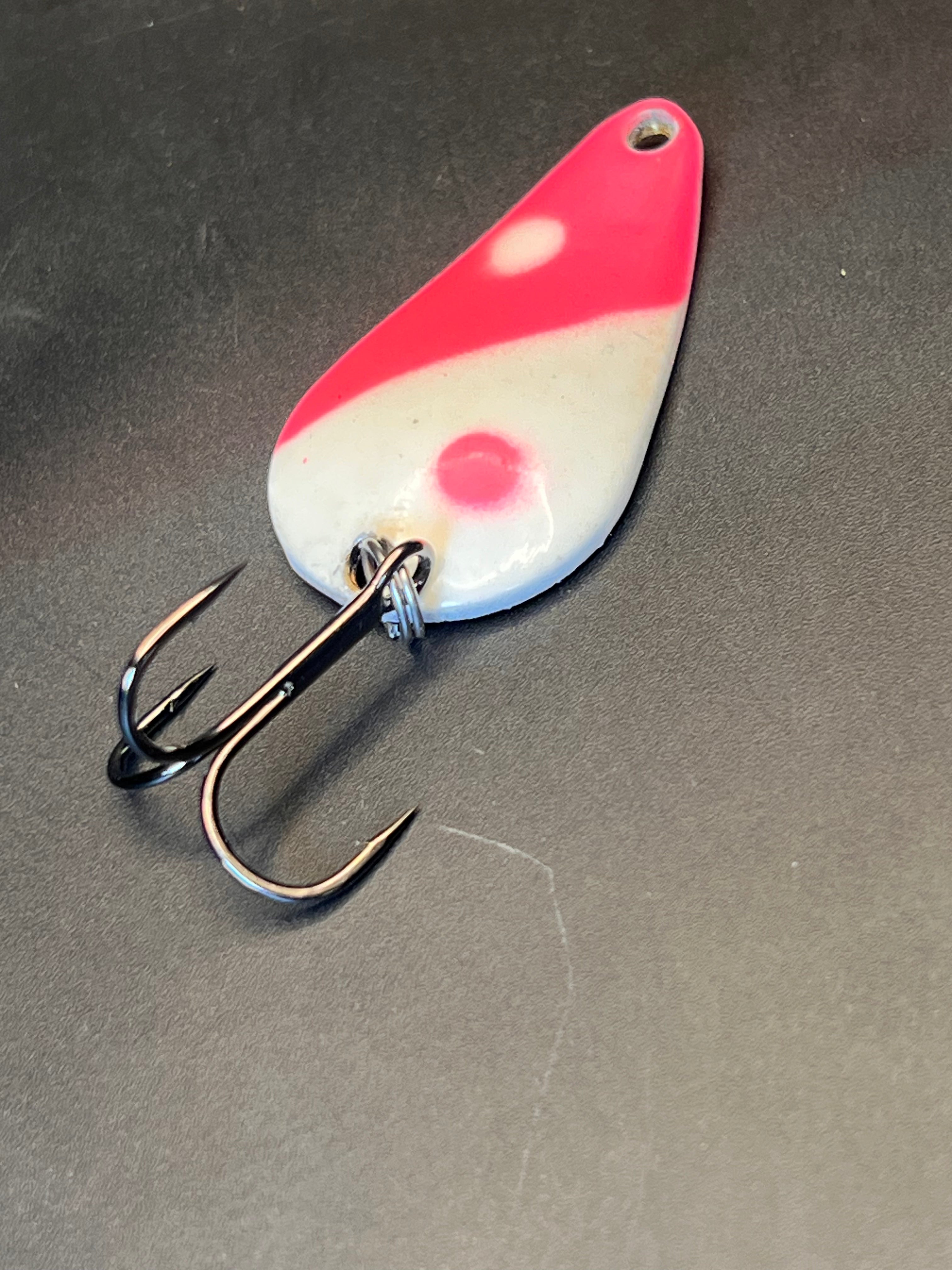Red and white fishing lure spoon with treble hook, casting spoon style