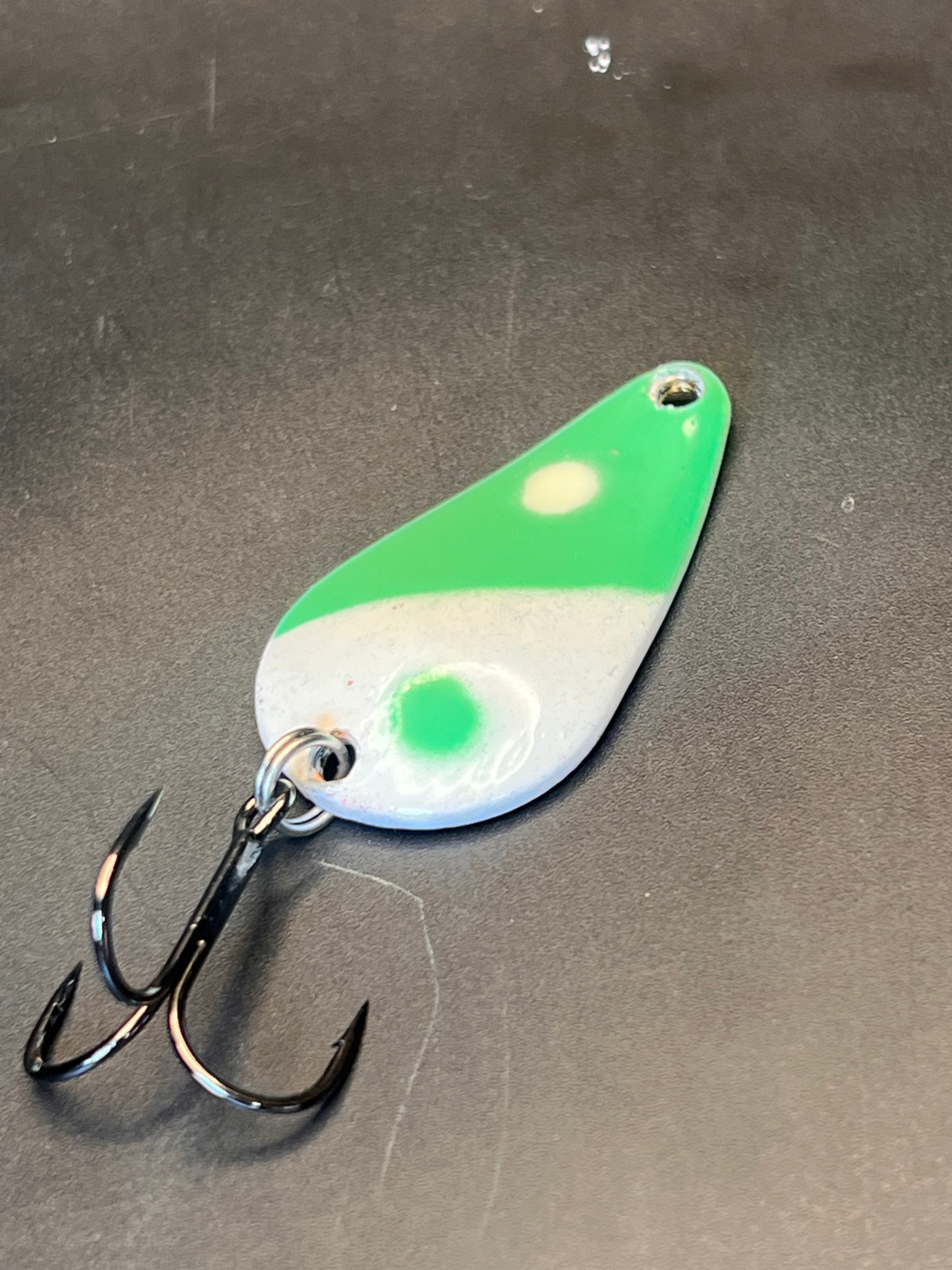 Green and white fishing lure spoon with treble hook, casting spoon style