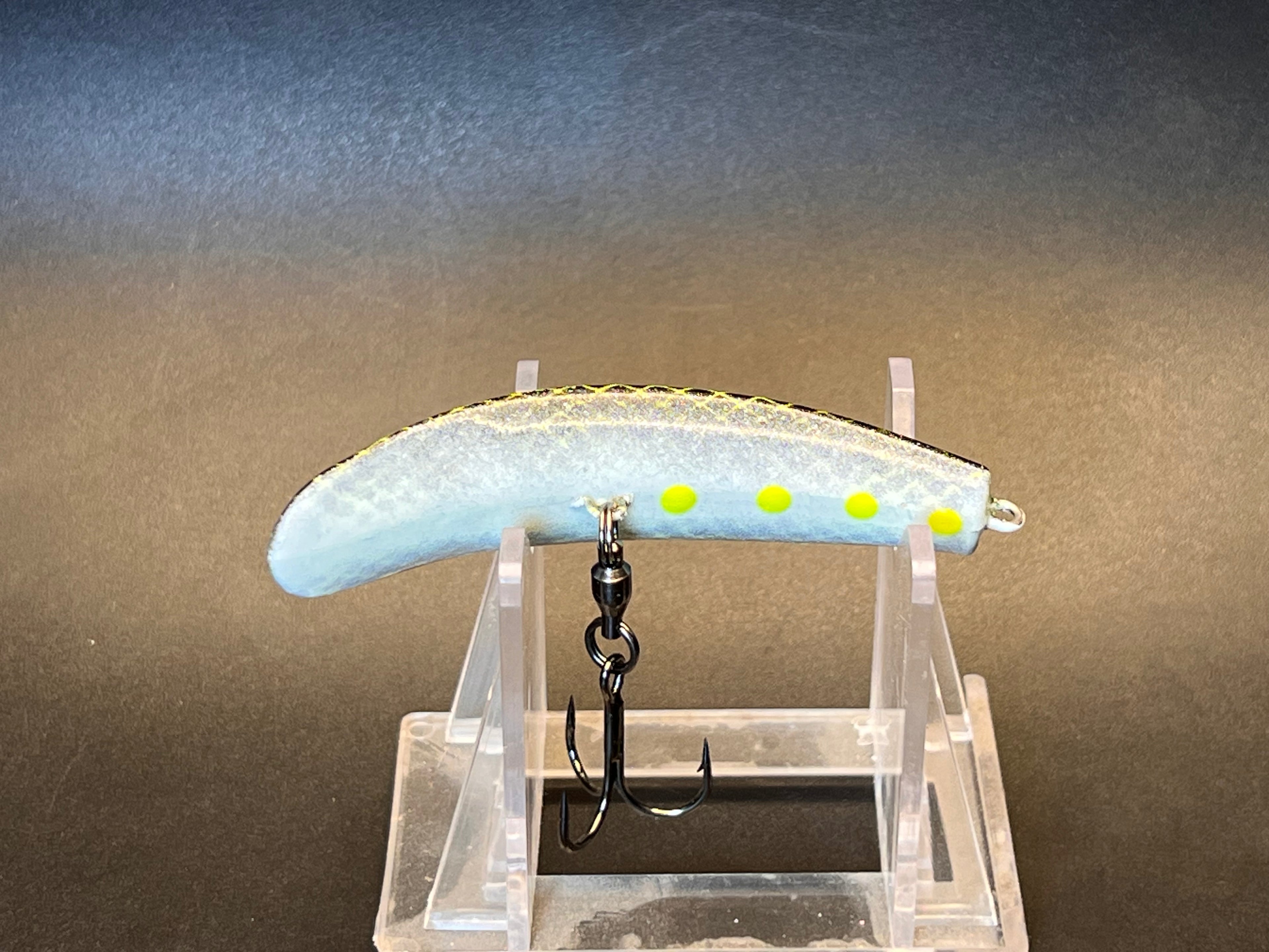 White and light-blue fish-shaped fishing lure with yellow eyes, two treble hooks